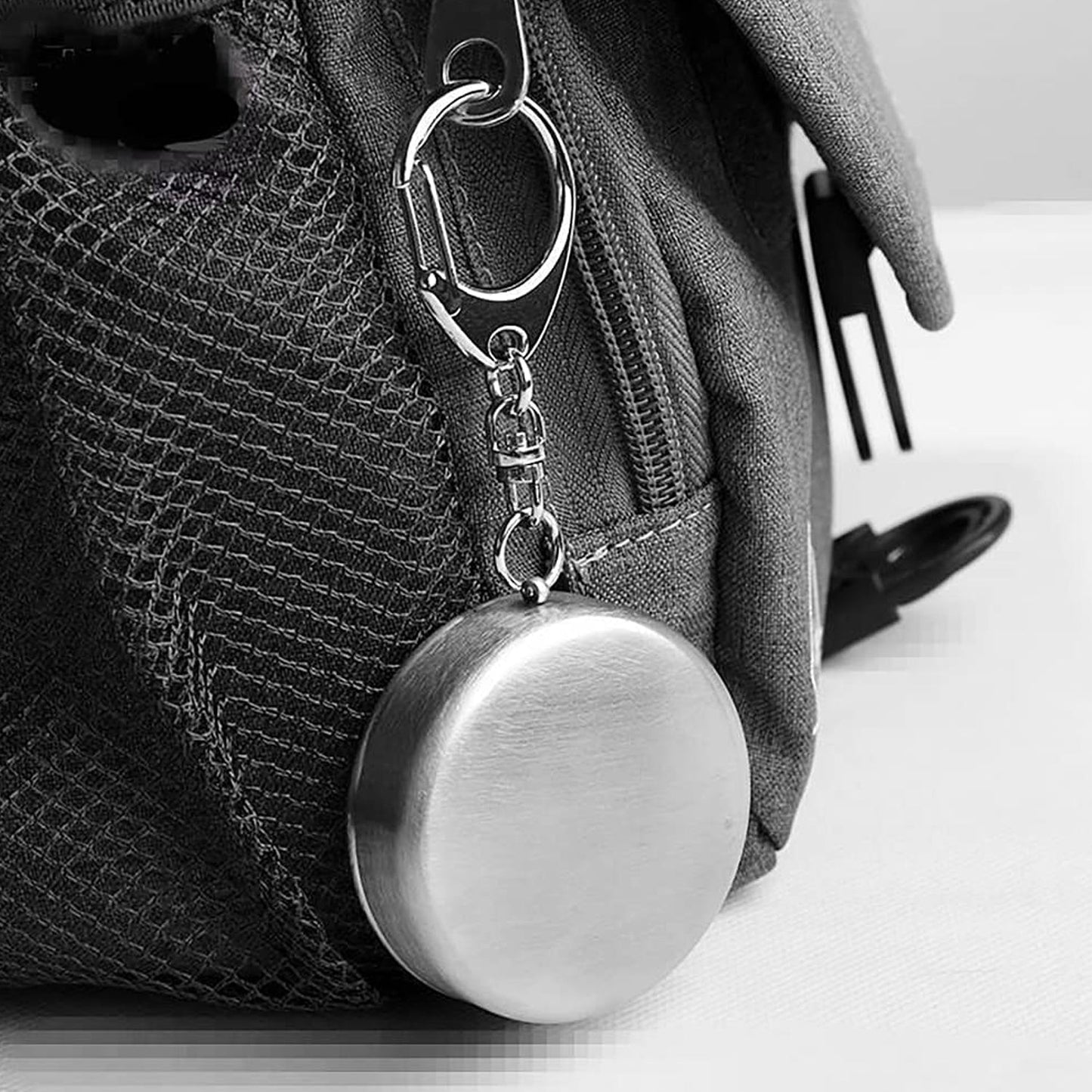 Ergonomic design of stainless steel camping cup held in hand.
