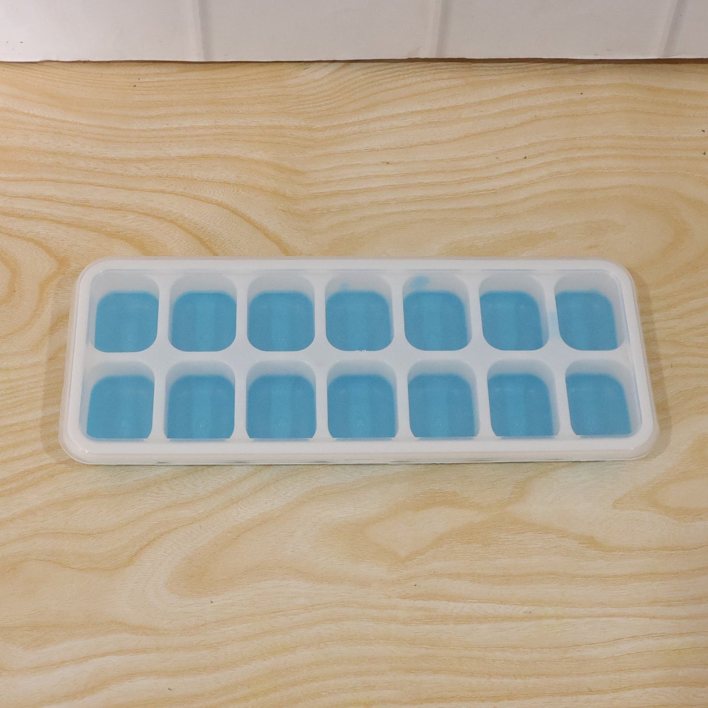 Clear plastic ice cube tray with water, ready for freezing