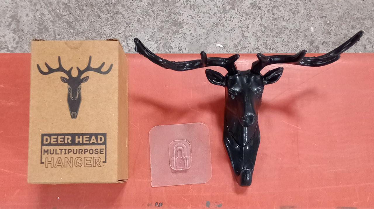 Three deer head wall hooks in black, white, and grey mounted on a wall.