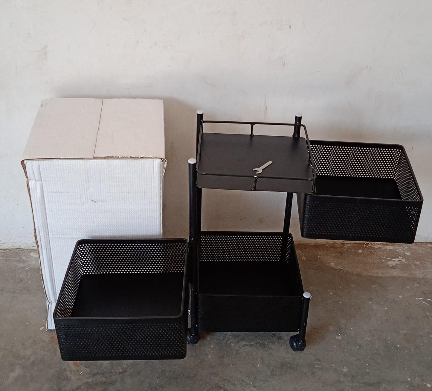 Fully assembled 3-layer metal kitchen trolley with wheels in a modern kitchen setting.
