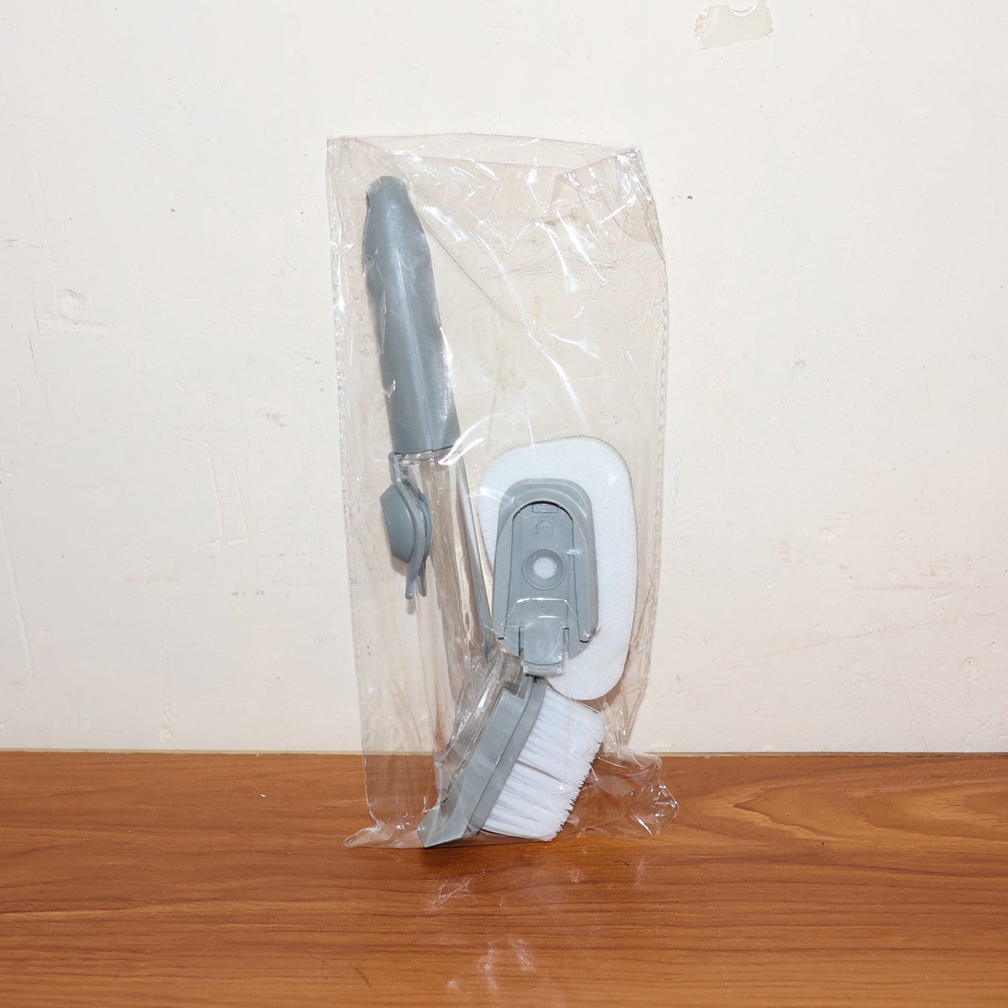 Soap-dispensing dish brush in action, cleaning food residue from a plate