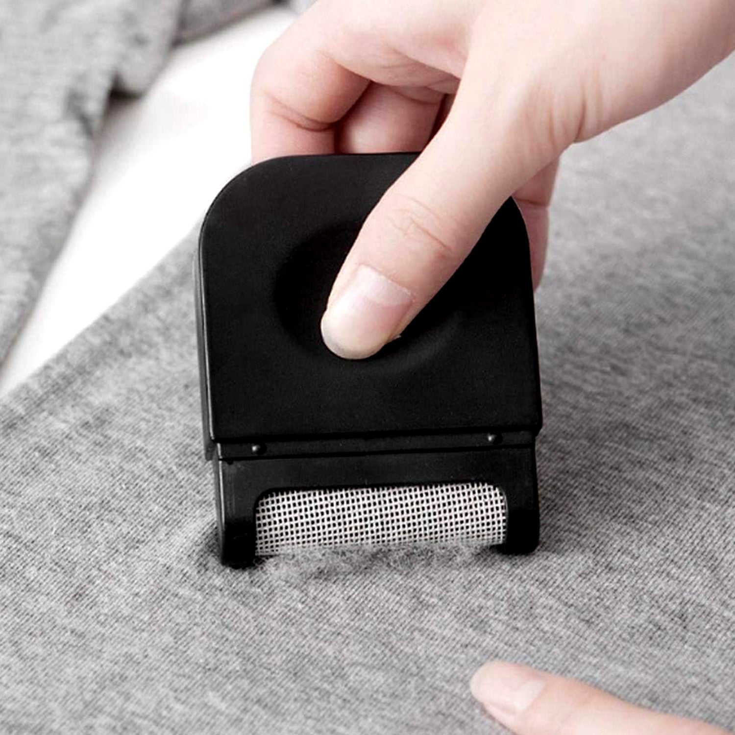 Lint remover demonstrating its detachable fuzz collection compartment.