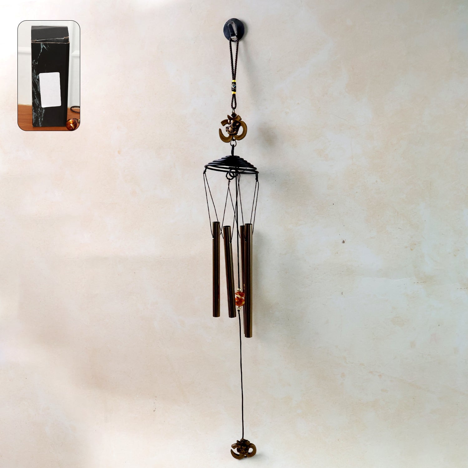 Metal wind chime with Om symbol hanging outdoors in a garden