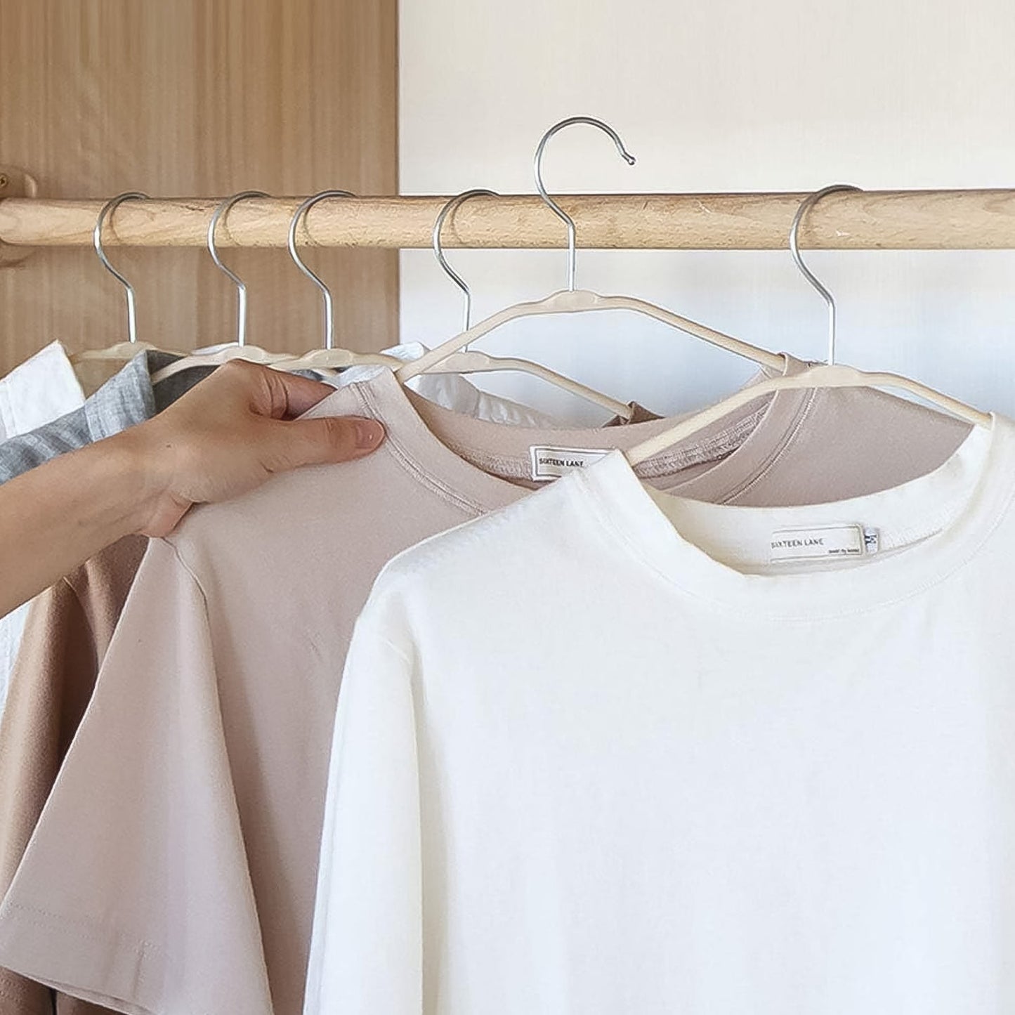 Multiple BathNova space-saving hangers neatly organized in a closet.