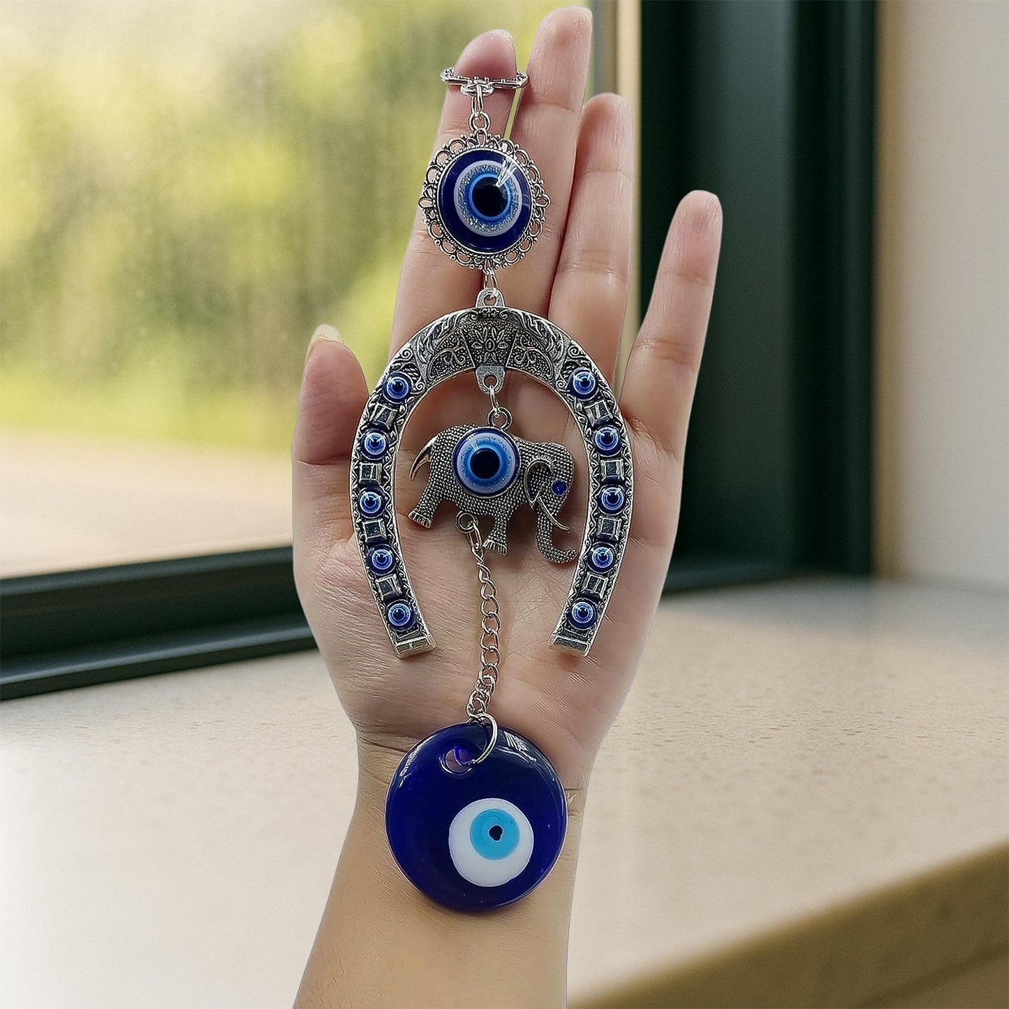 Close-up of alloy metal evil eye hanging with chain and elephant motif