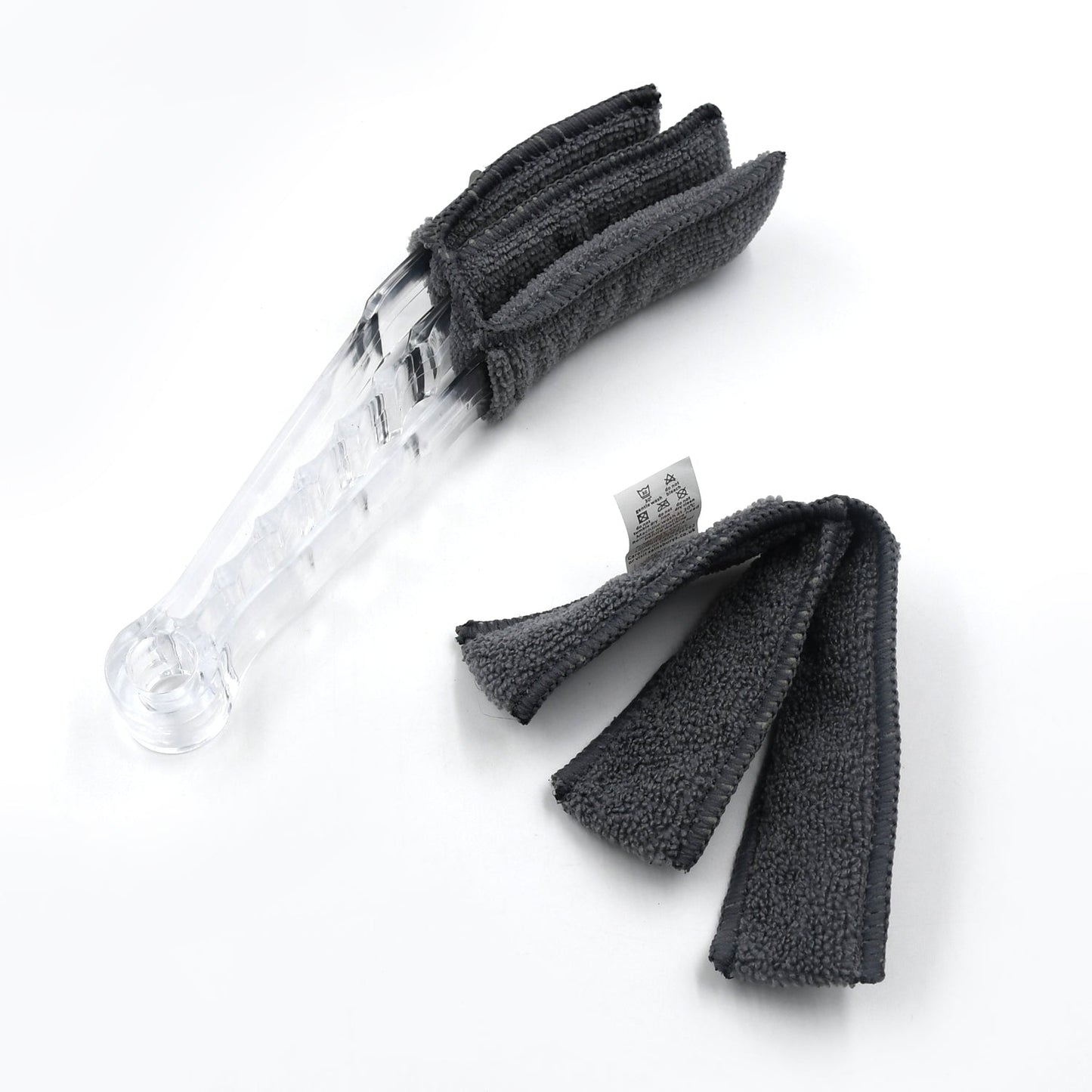 The compact blind cleaner brush being used to clean dust from a car's AC vent.