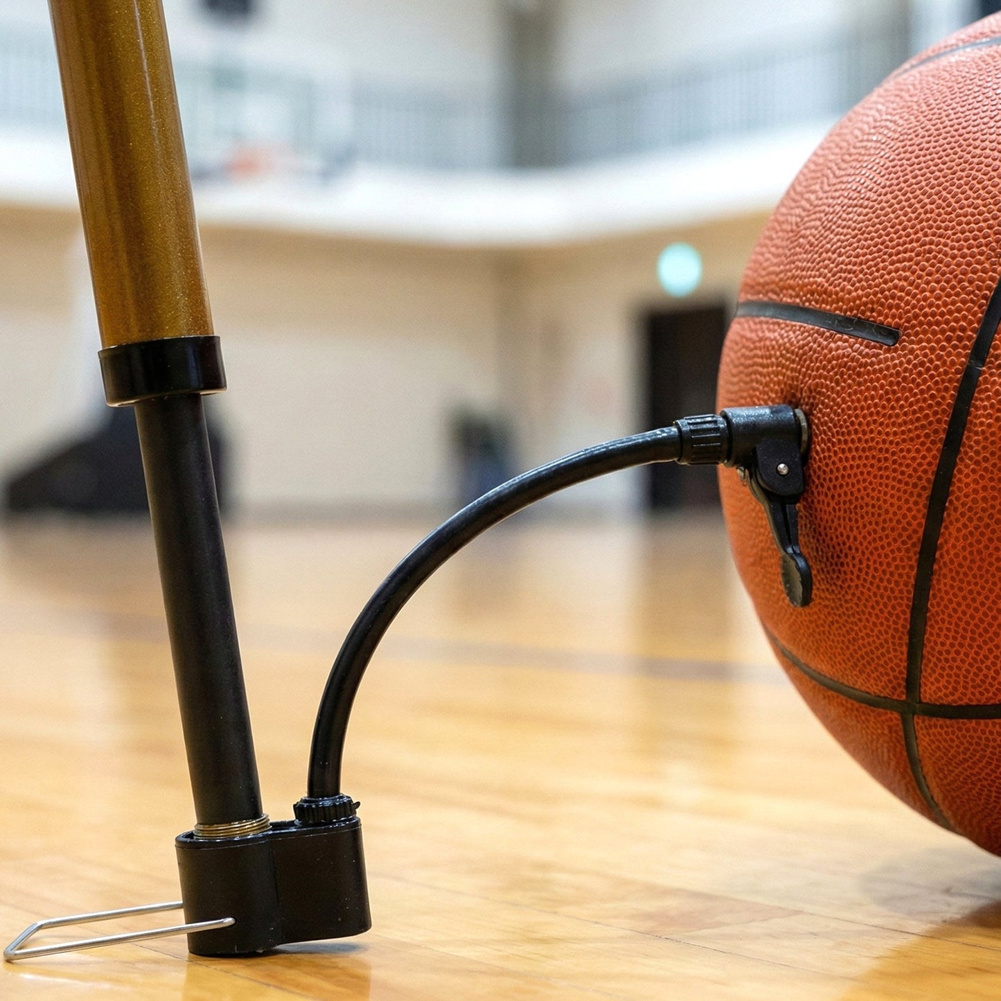 A user easily inflates a basketball using the portable Mini Hand Air Pump with its attached needle.