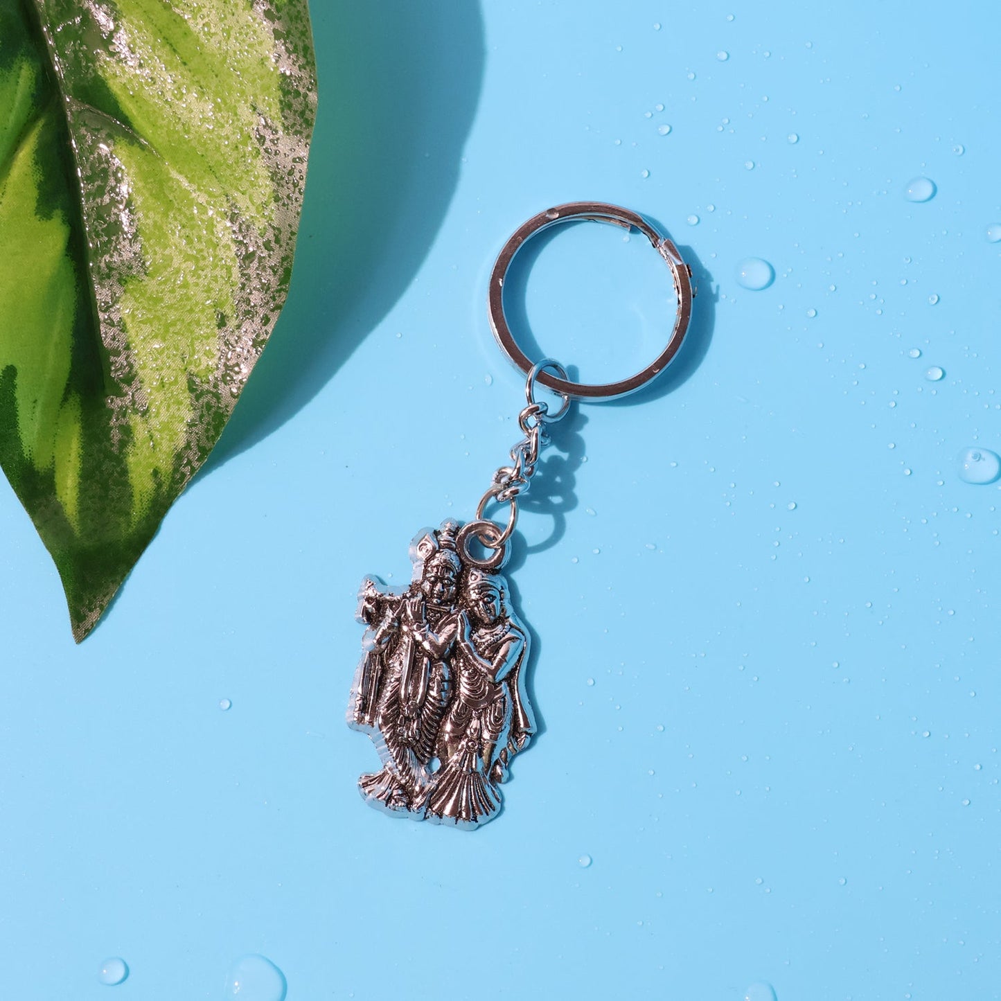 Front view of Radha Krishna metal keychain showing detailed spiritual motifs