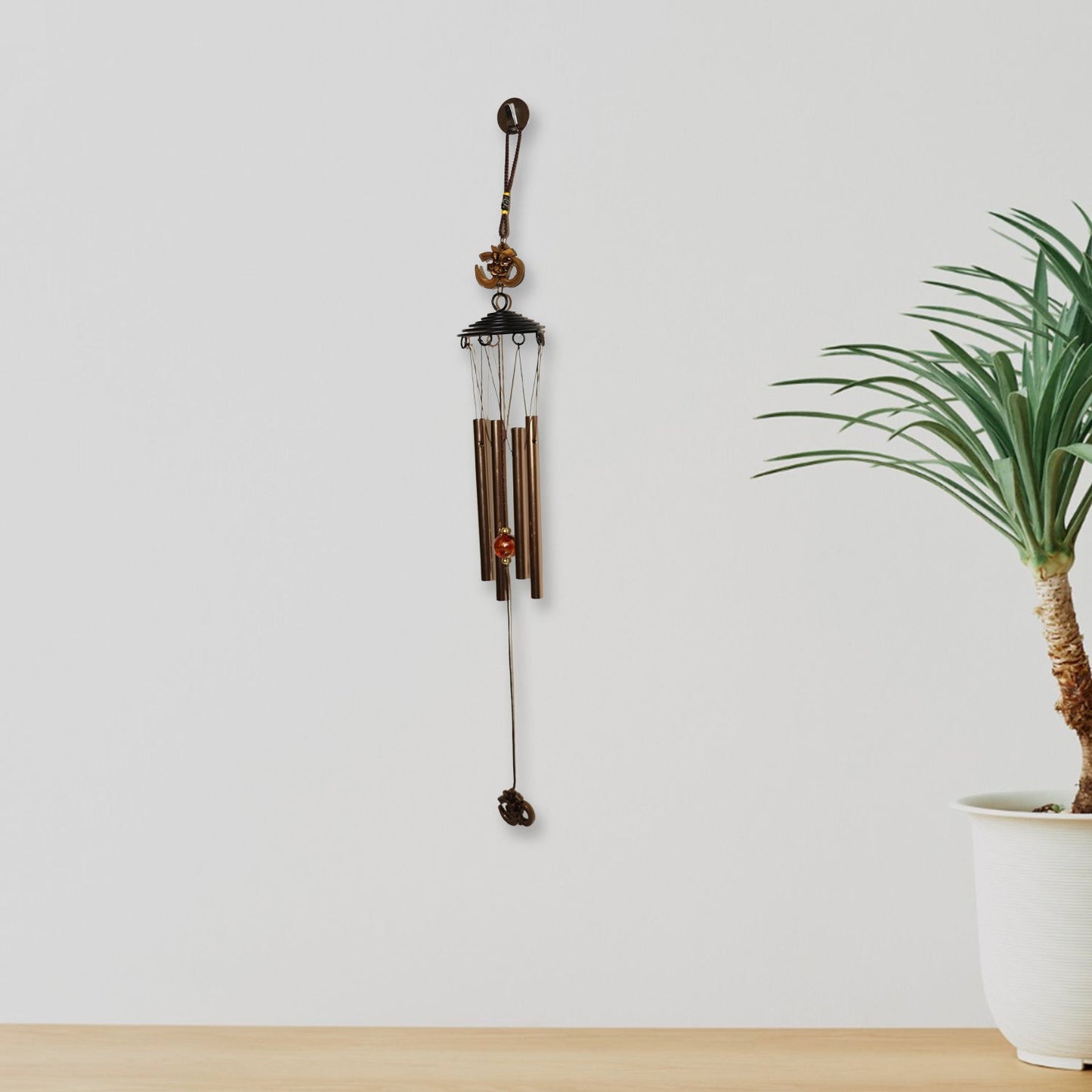 Close side shot of metal wind chime with Om symbol and metal tubes