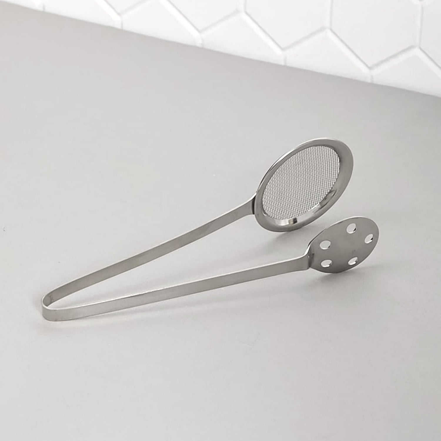 Polished steel serving tong with dual mesh and perforated sides for draining food