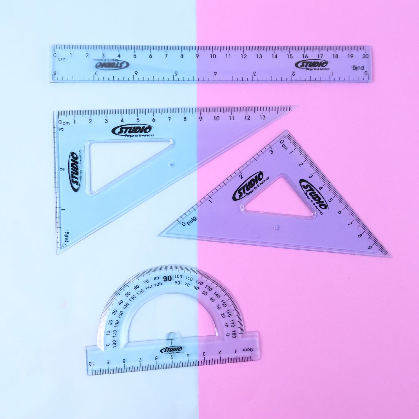 Transparent geometry tools laid out on surface showing ruler, protractor and set squares