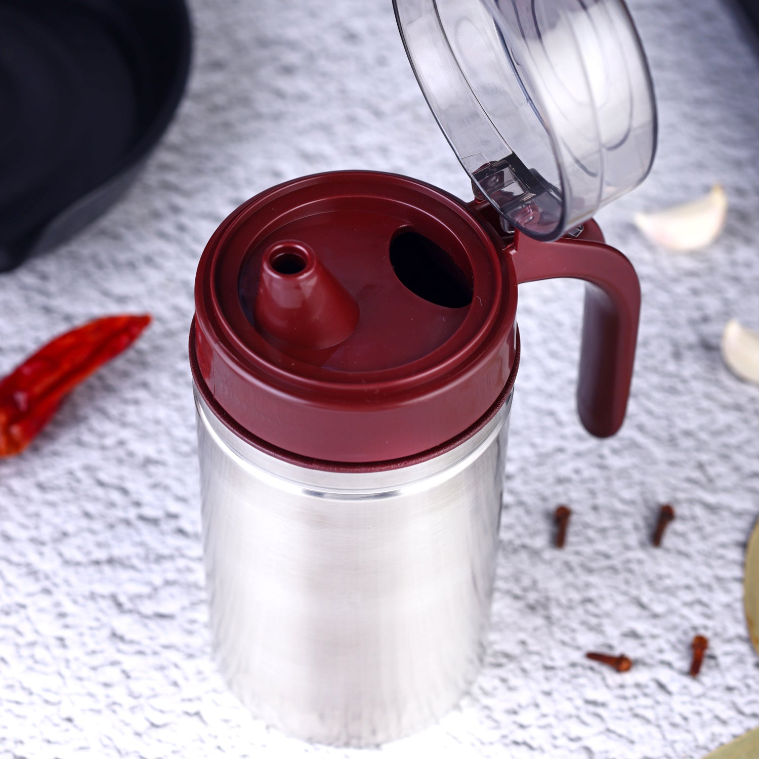 Stainless steel oil container with its small nozzle and lid, ready for use.