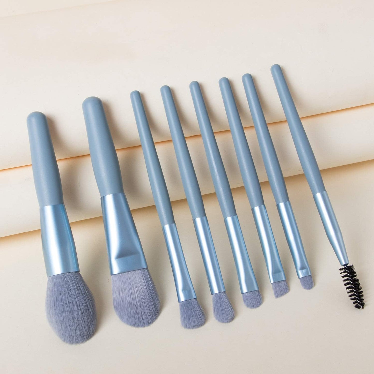 A person holding a blending brush from the 8-piece mini makeup brush set, demonstrating its size.