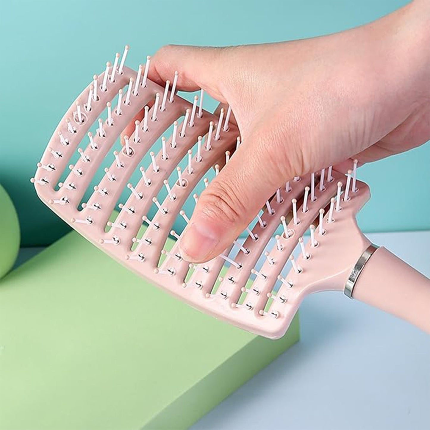 Massage hair comb held by hand showing anti-slip handle for comfortable styling