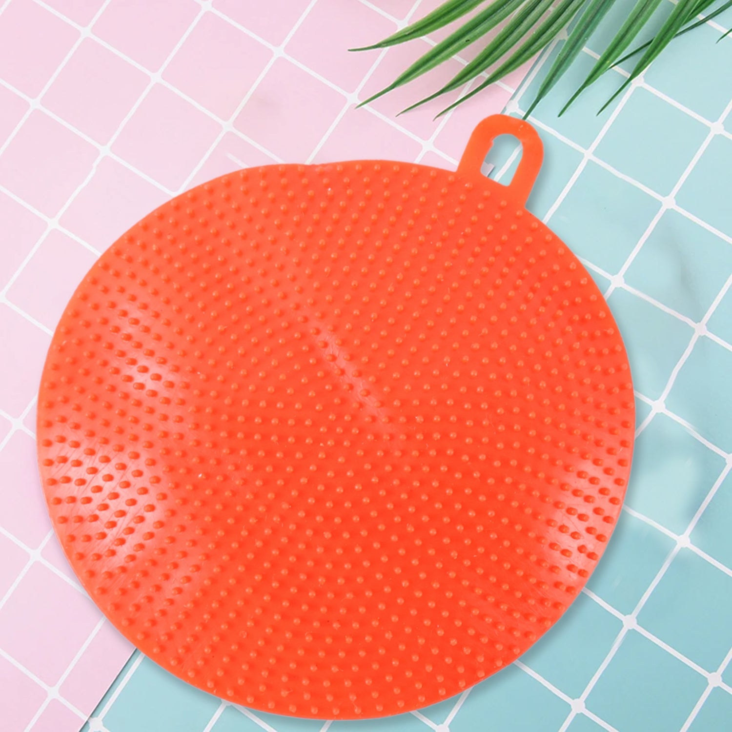 Red silicone dish scrubber hanging to dry after washing