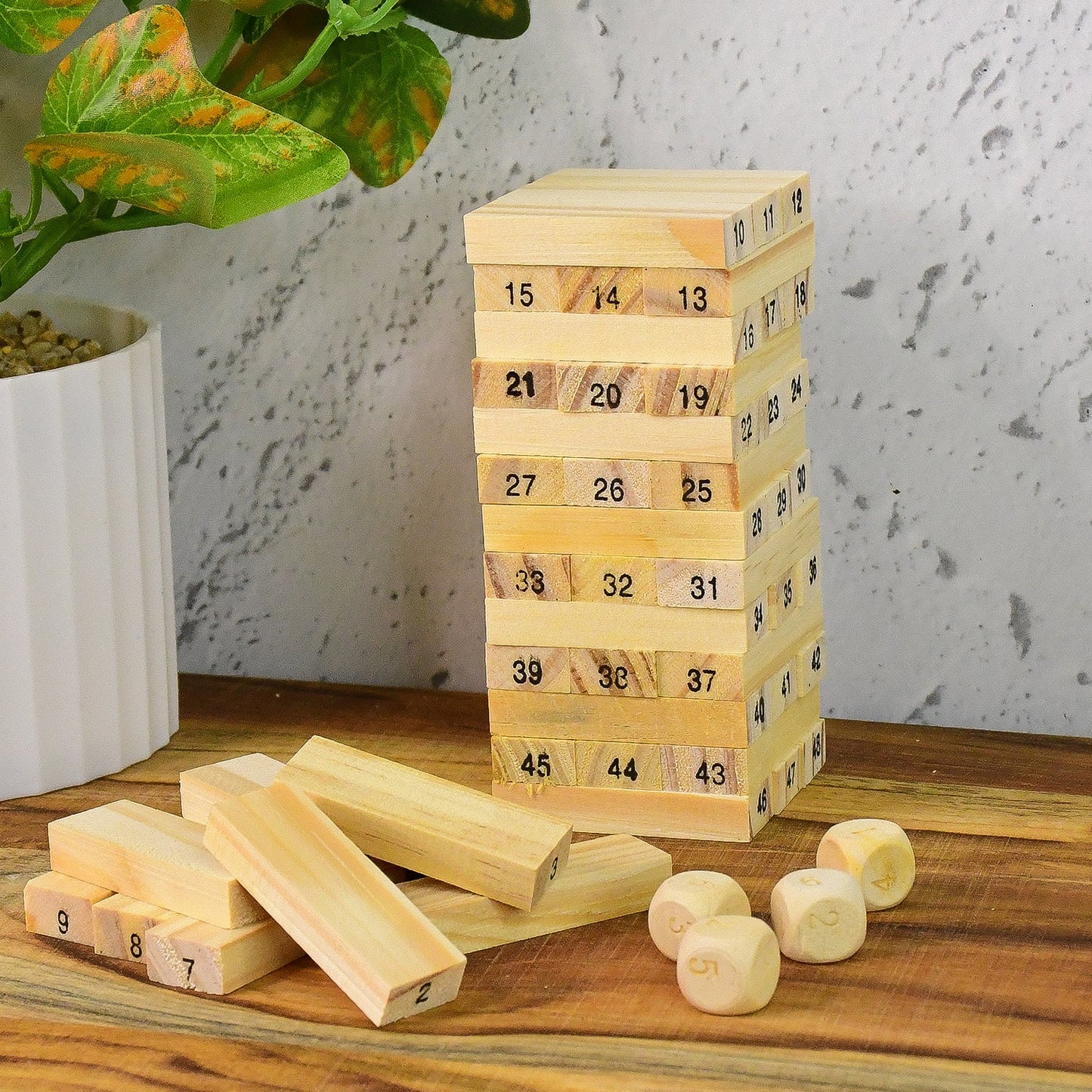A child's hands attempting to extract a block from the precarious wooden tower during a game.