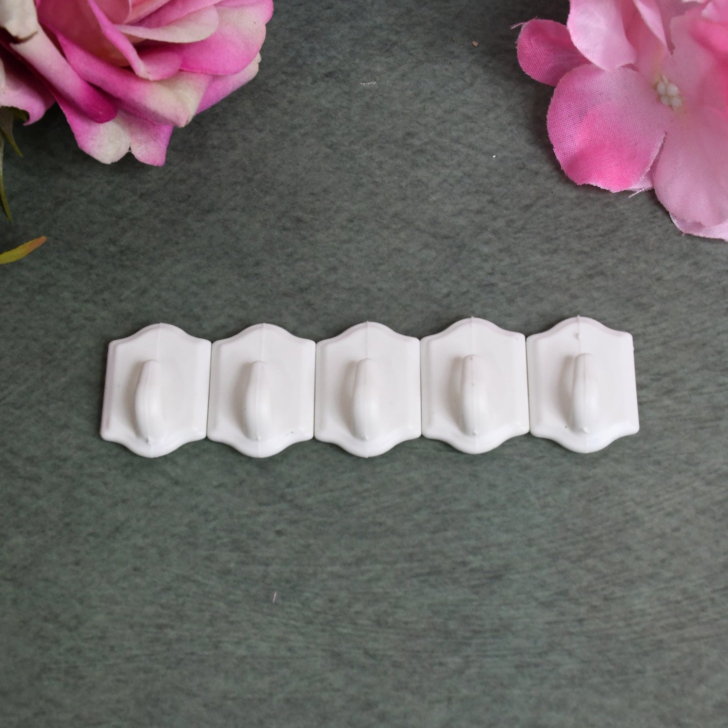 Adhesive wall hooks demonstrated holding kitchen utensils on a tiled wall.