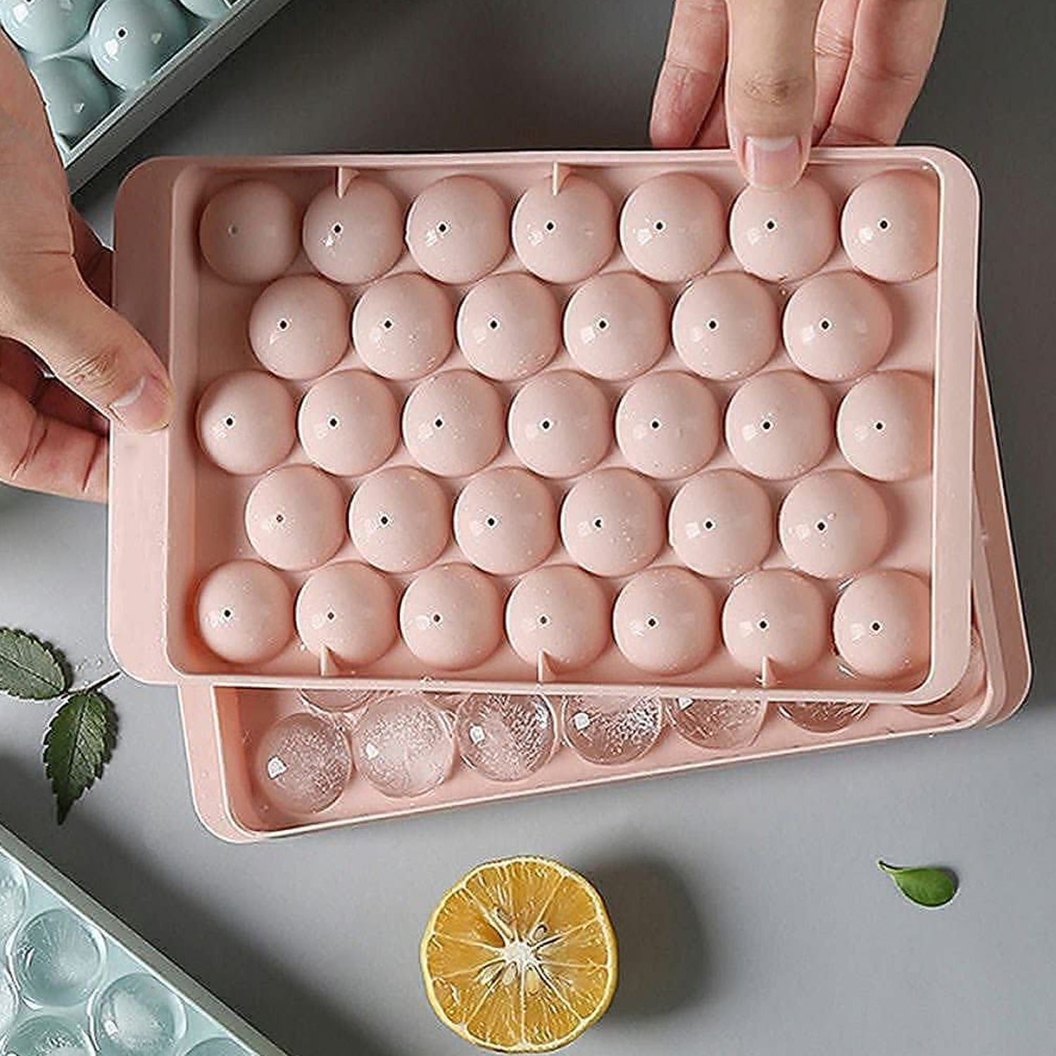 The  ice ball mold alongside a glass of chilled beverage, ready for serving.