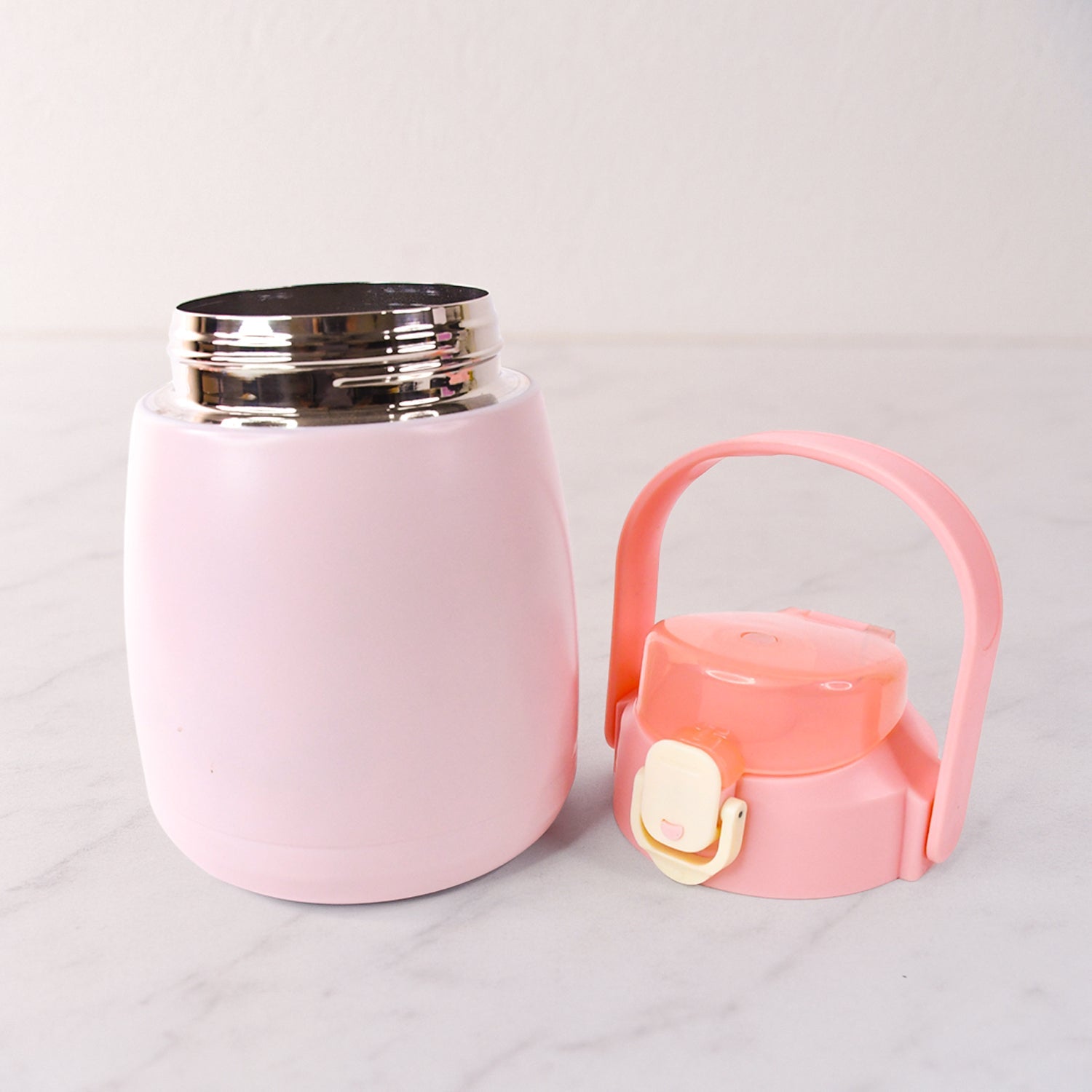 Insulated stainless steel water bottle with handle placed on a table
