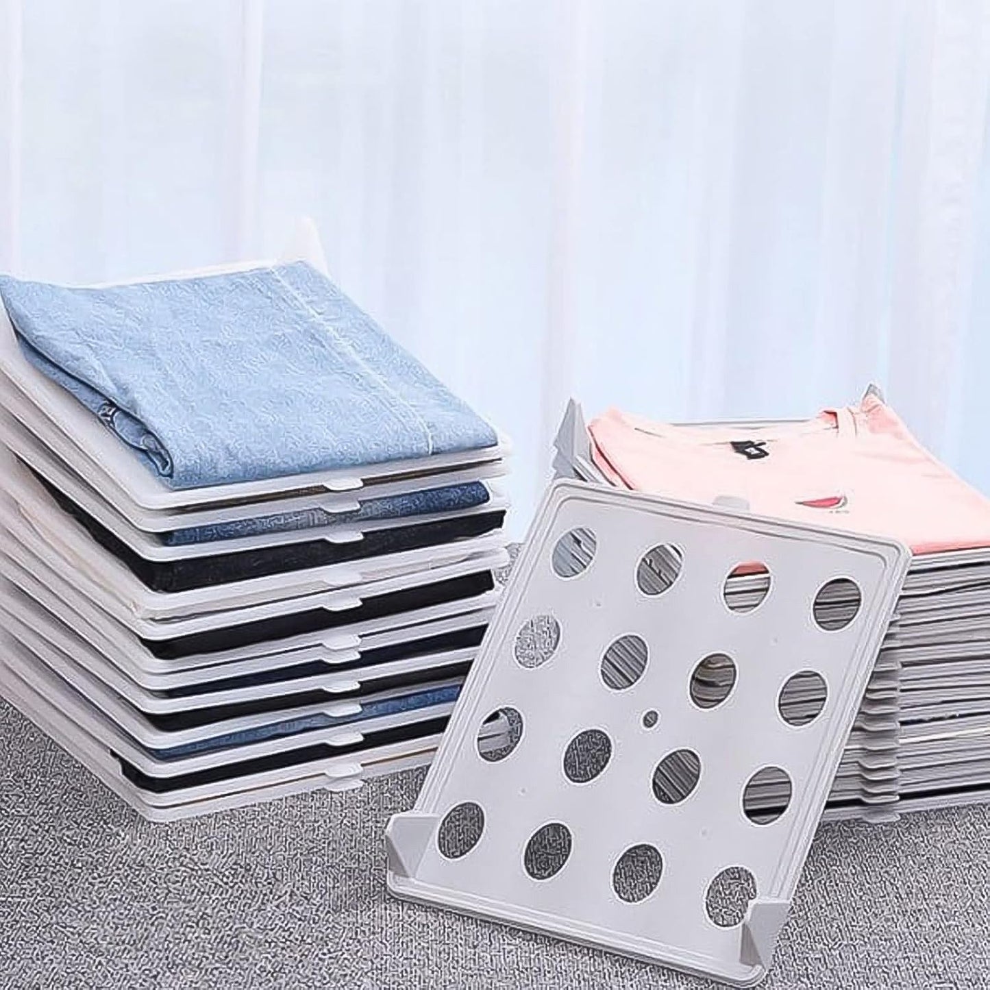 Versatile Clothes Folding Board used to organize various clothing items like pants and sweaters.