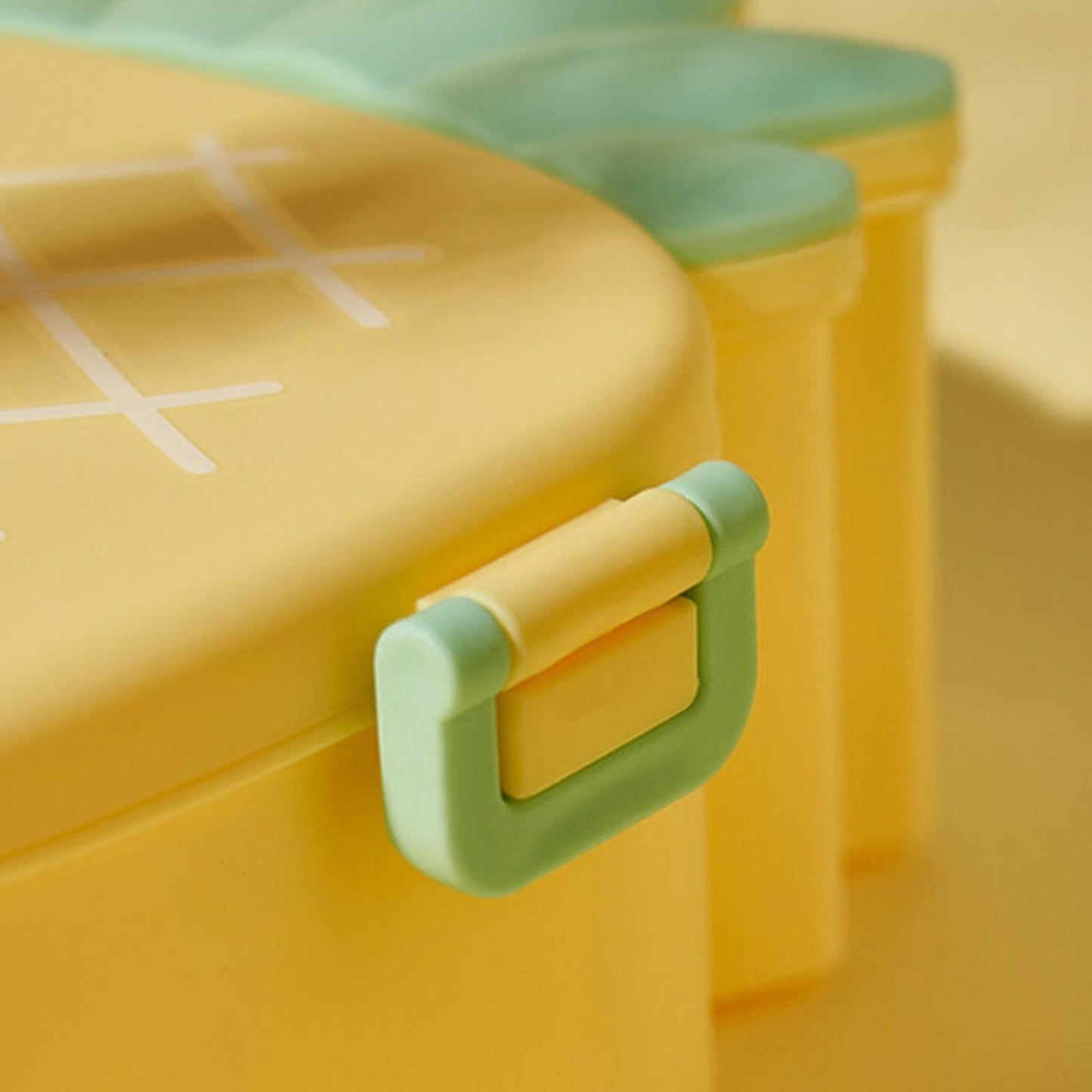Child's hand opening the vibrant pineapple bento lunch box to reveal compartments.
