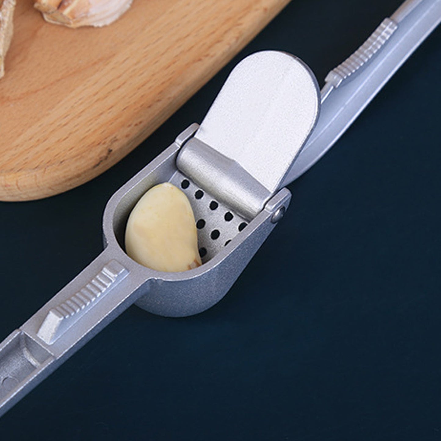 Aluminum garlic press on a kitchen counter, ready for use.
