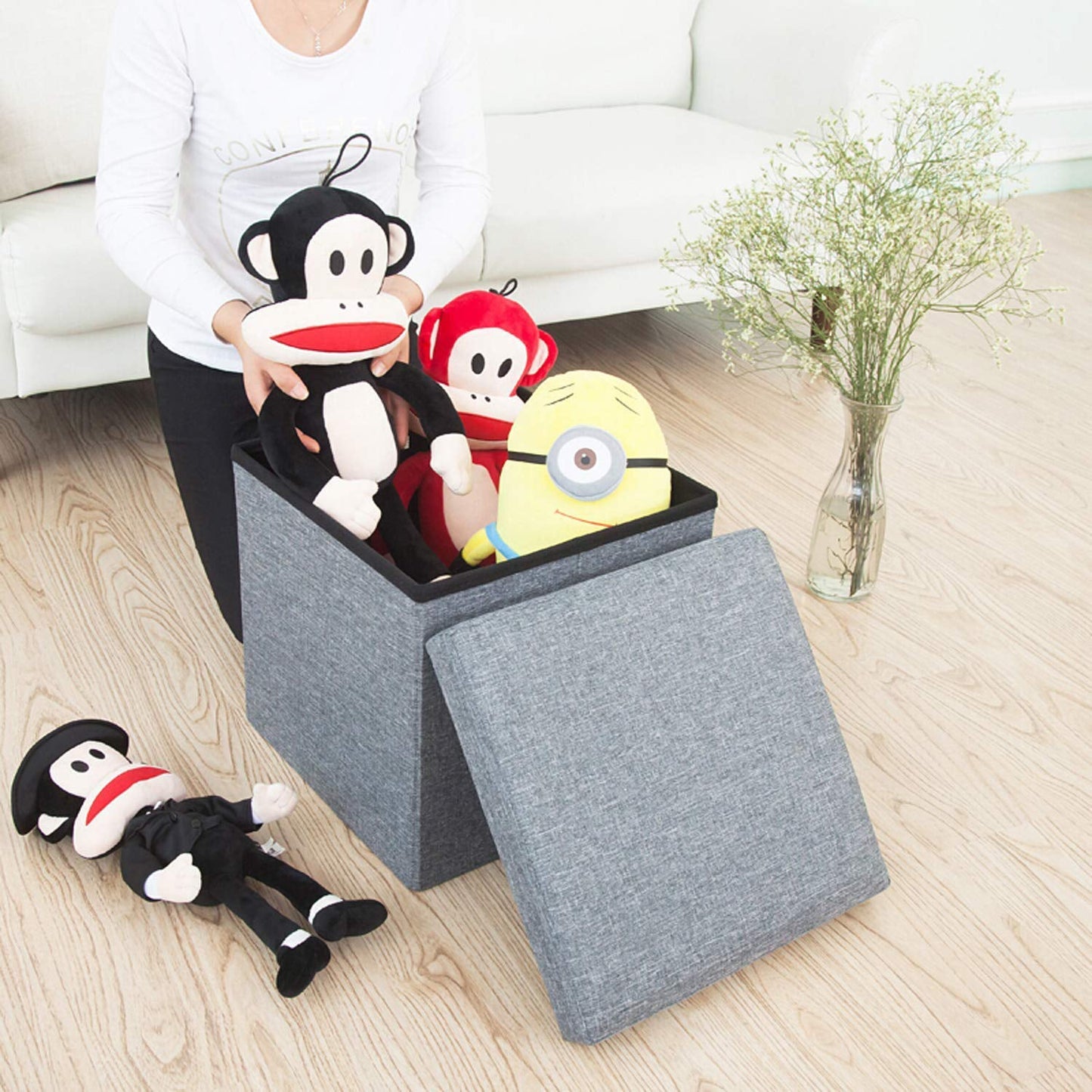 A stylish grey foldable storage stool with a comfortable cushion top, perfect for living room organization.
