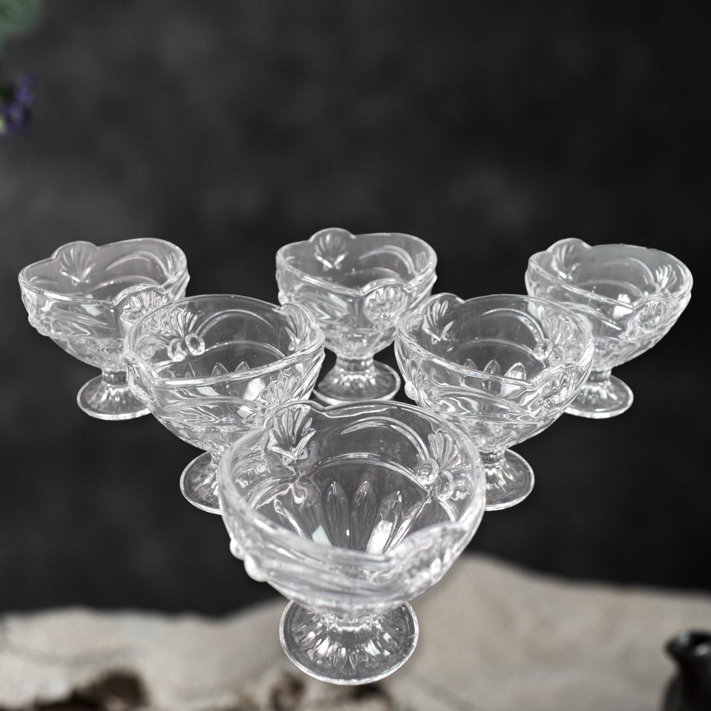Three glass dessert bowls displayed from an angle, emphasizing their clear finish.