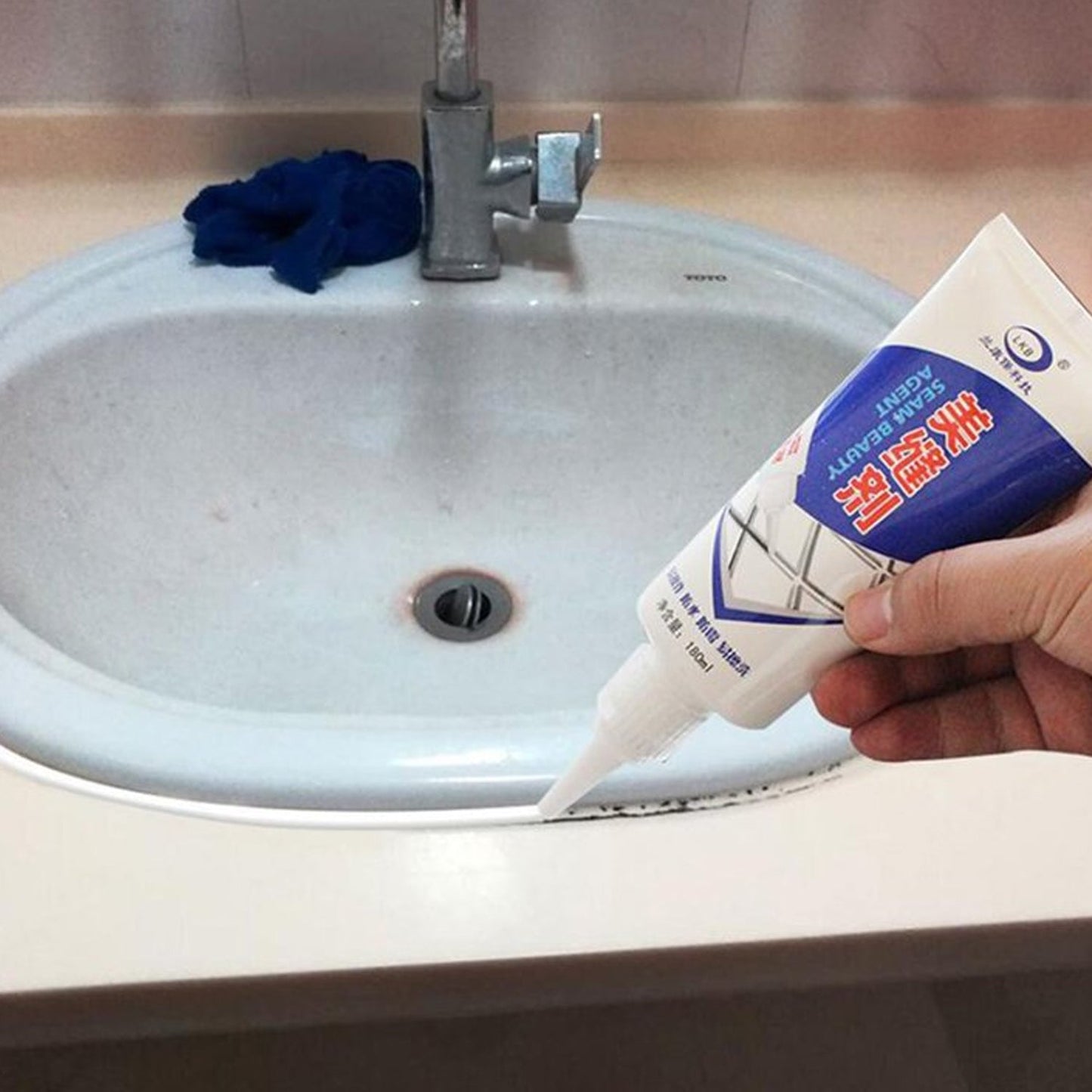Close-up view of fresh silicone sealant smoothing a tiled kitchen backsplash grout line.
