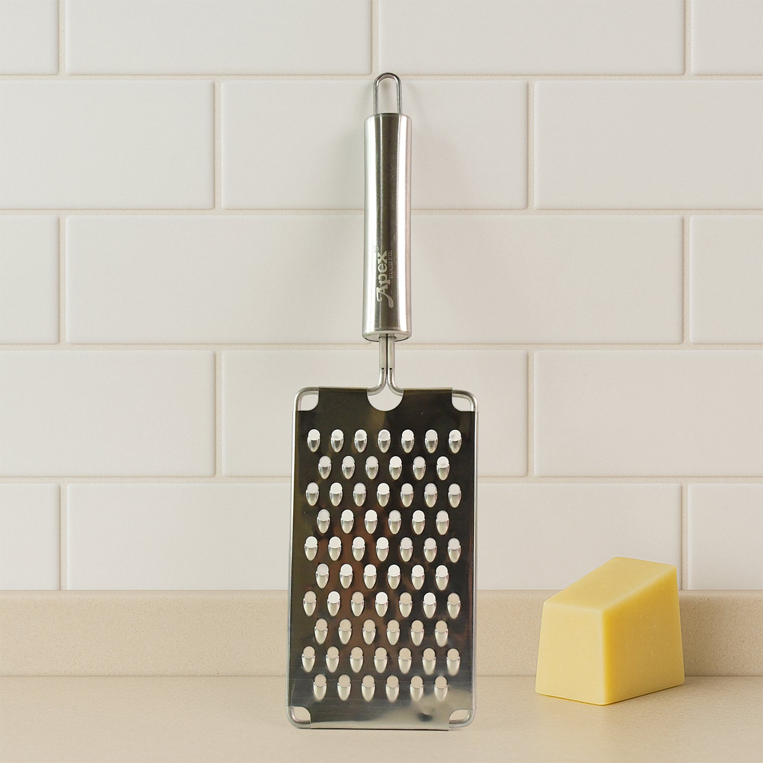 Flat handheld stainless steel vegetable grater in use grating carrots