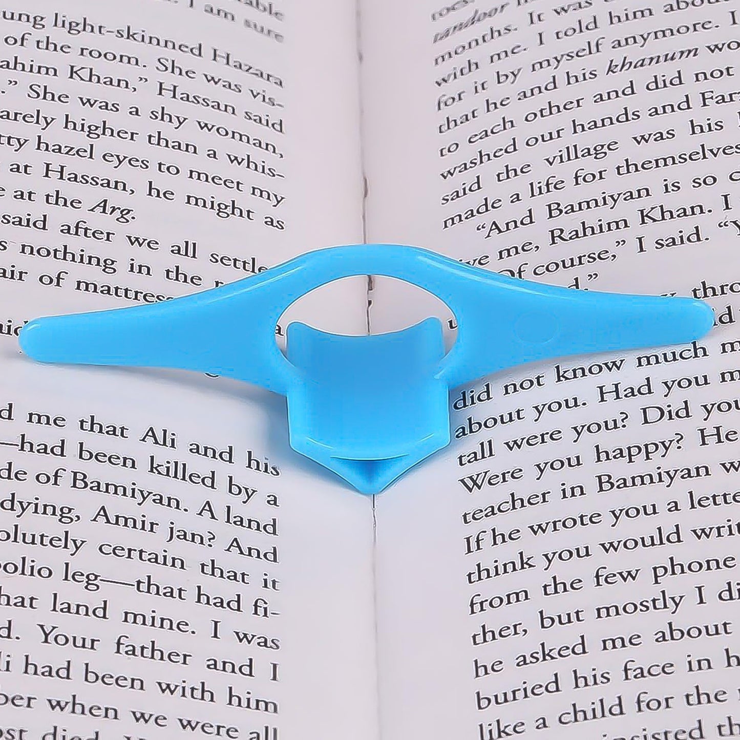 Person comfortably reading a book held open by the plastic thumb page holder.