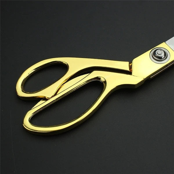 Detailed view of the blade and pivot point of the golden tailoring scissor.
