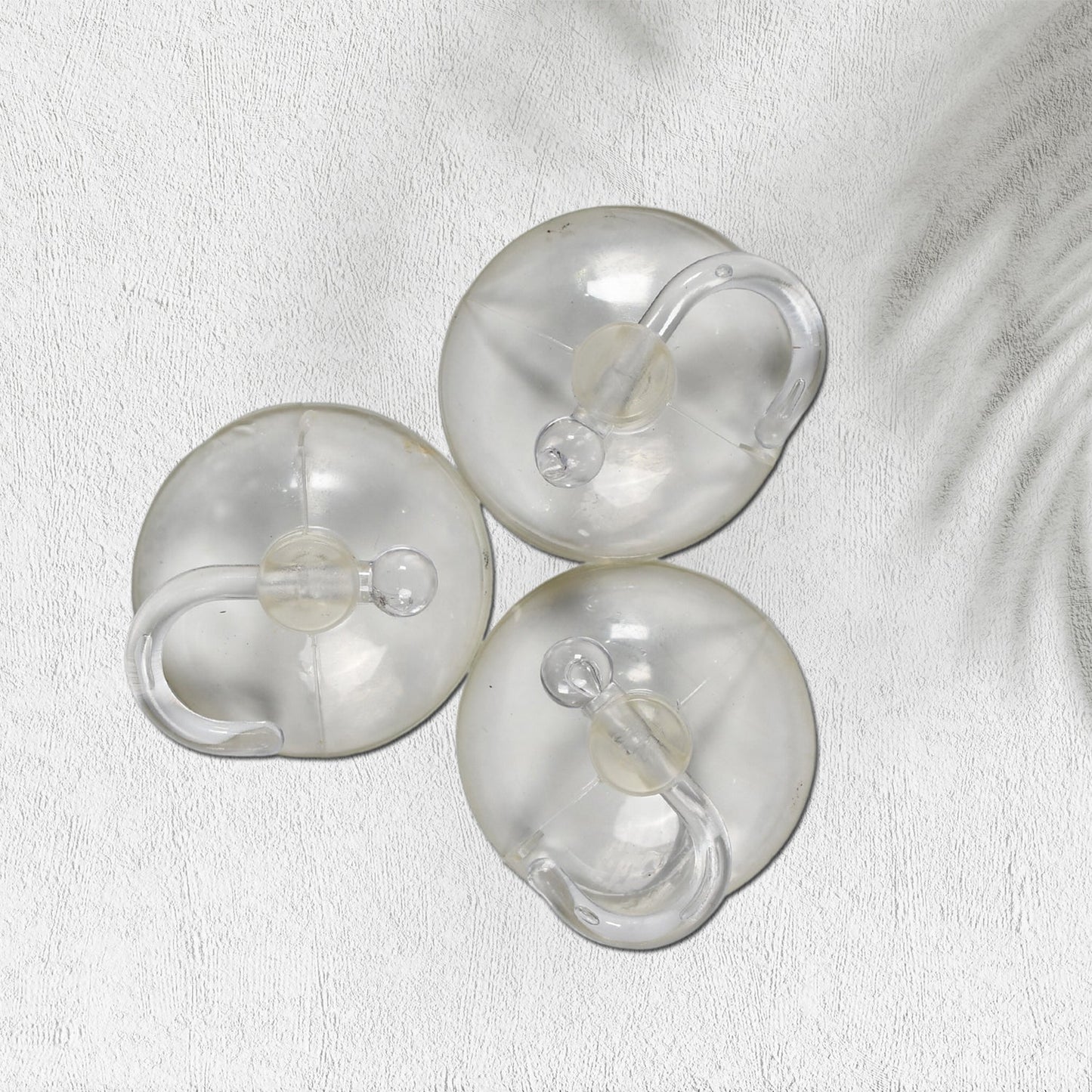 Two transparent suction hooks with strong hold on a bathroom tile wall.