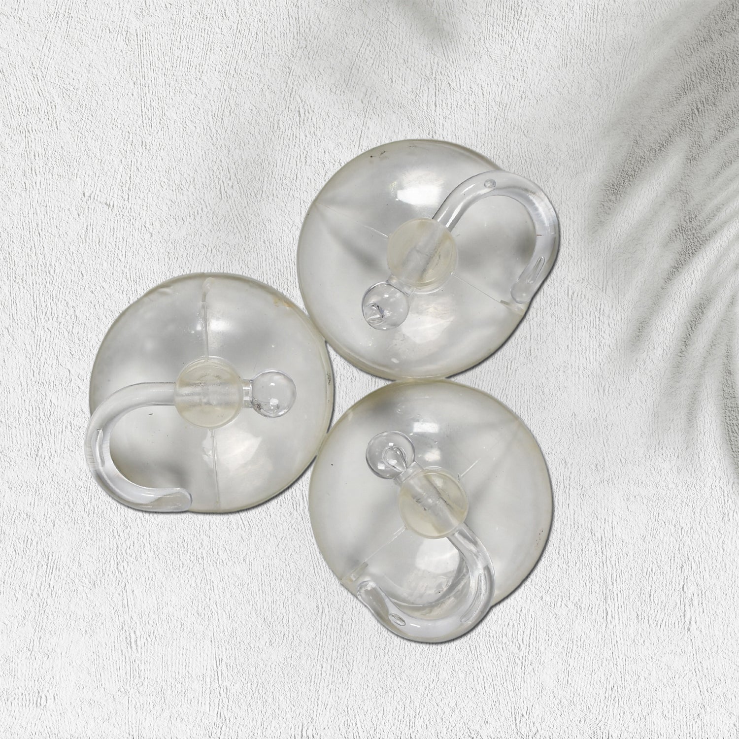 Two transparent suction hooks with strong hold on a bathroom tile wall.