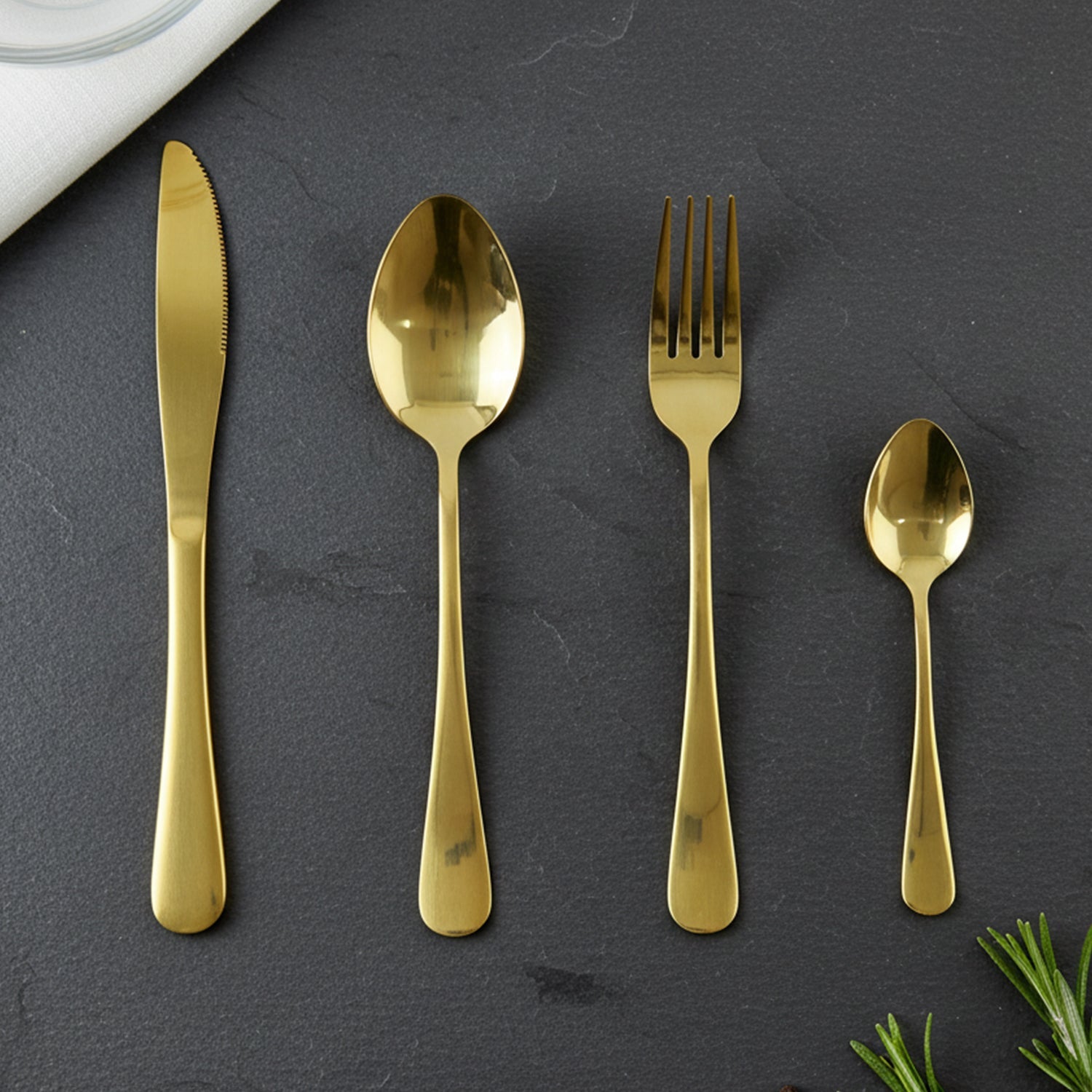Gold spoons, forks, and knives laid out showcasing the set's completeness