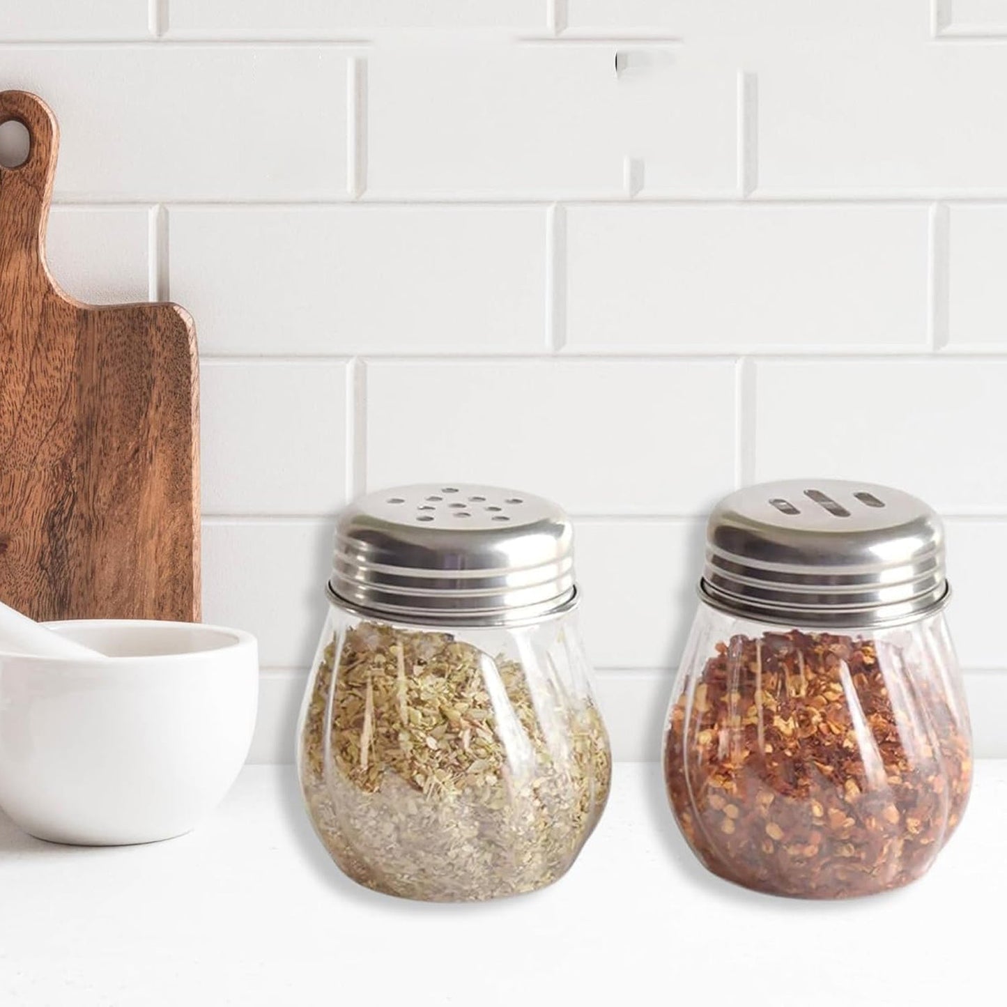 Oregano & Chilli Flakes Dispenser Set with clear plastic body and stainless steel lids on kitchen counter