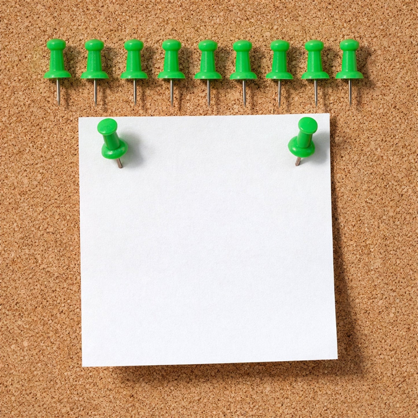 Green push pin fixing paper on a cork notice board