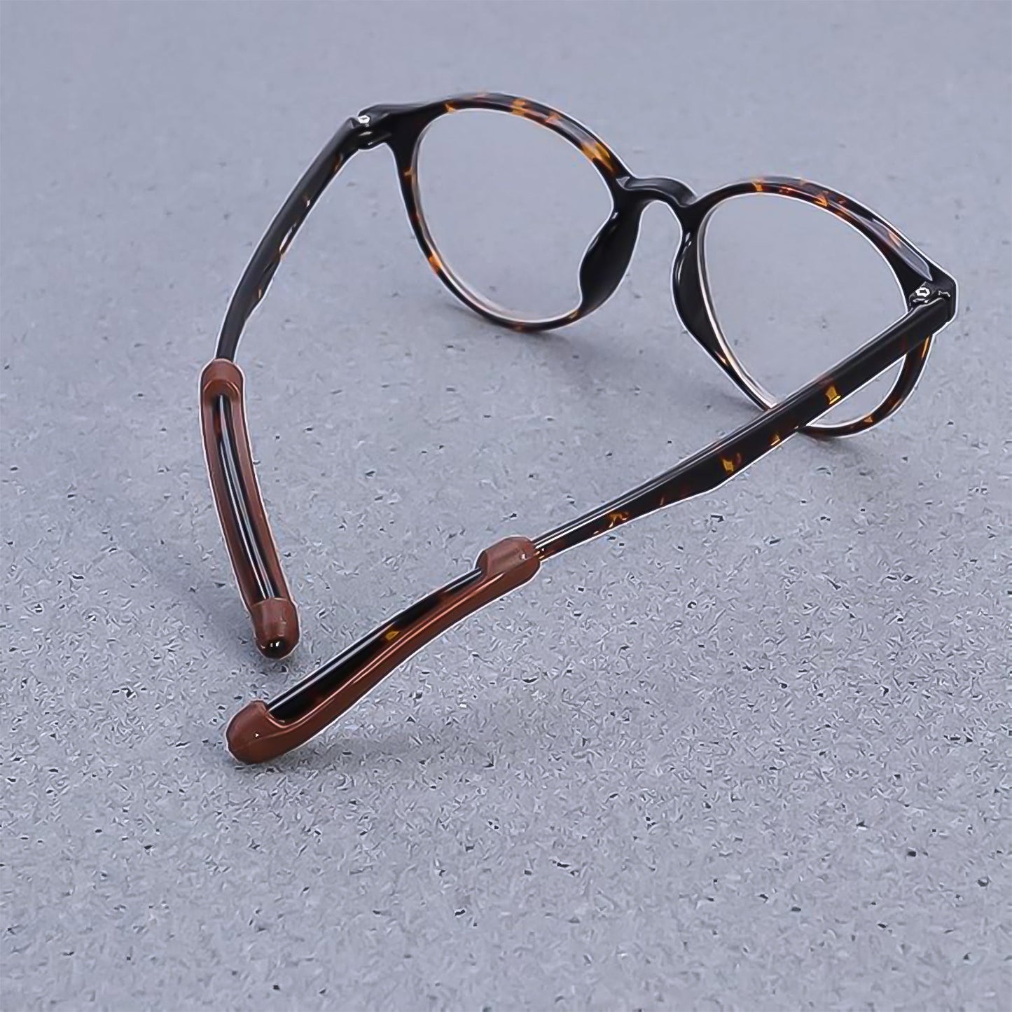 Silicone ear grips attached to eyeglass arms, demonstrating how they prevent glasses from slipping.