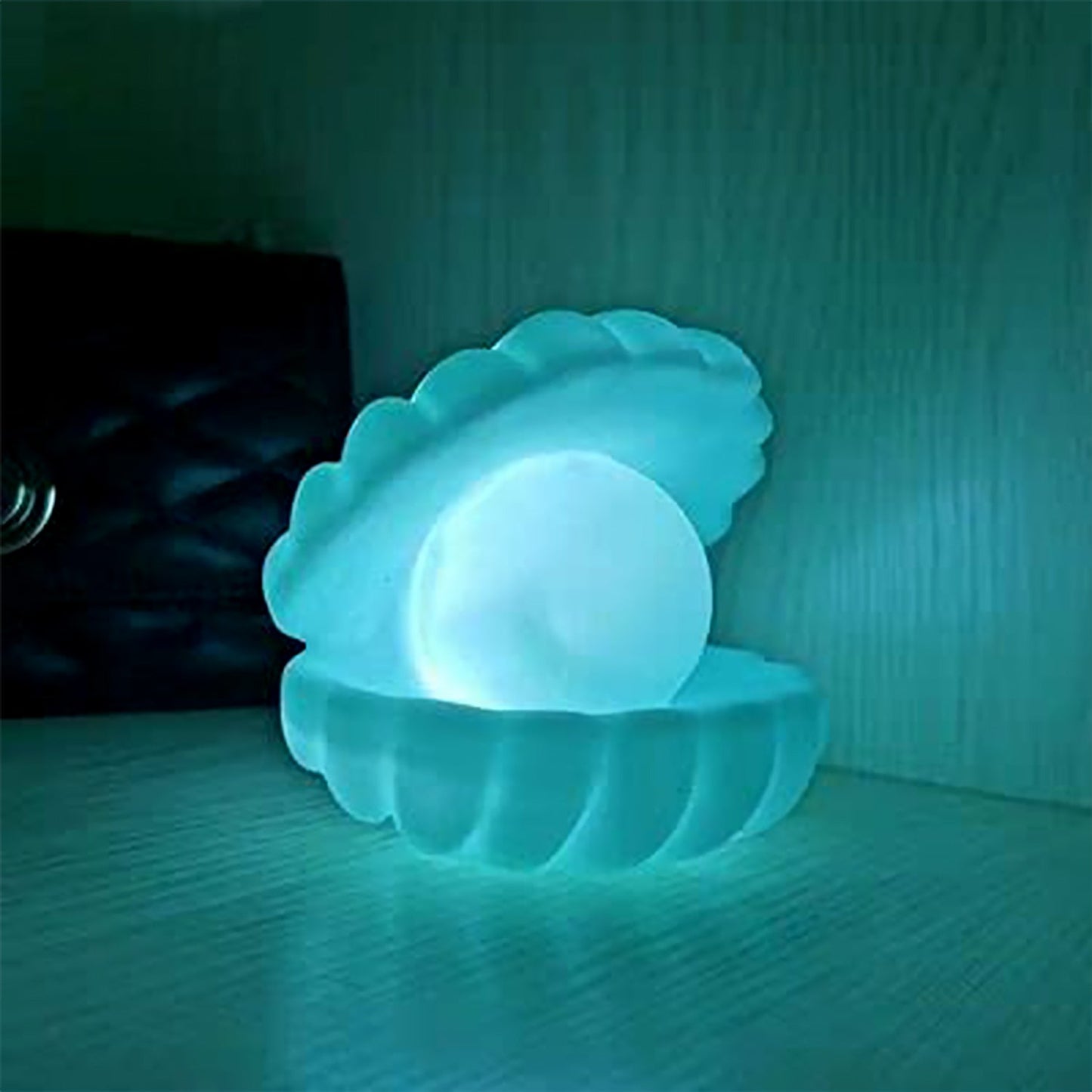 The Pearl Shell Night Lamp placed on a wooden desk next to a plant, enhancing the room's ambiance.