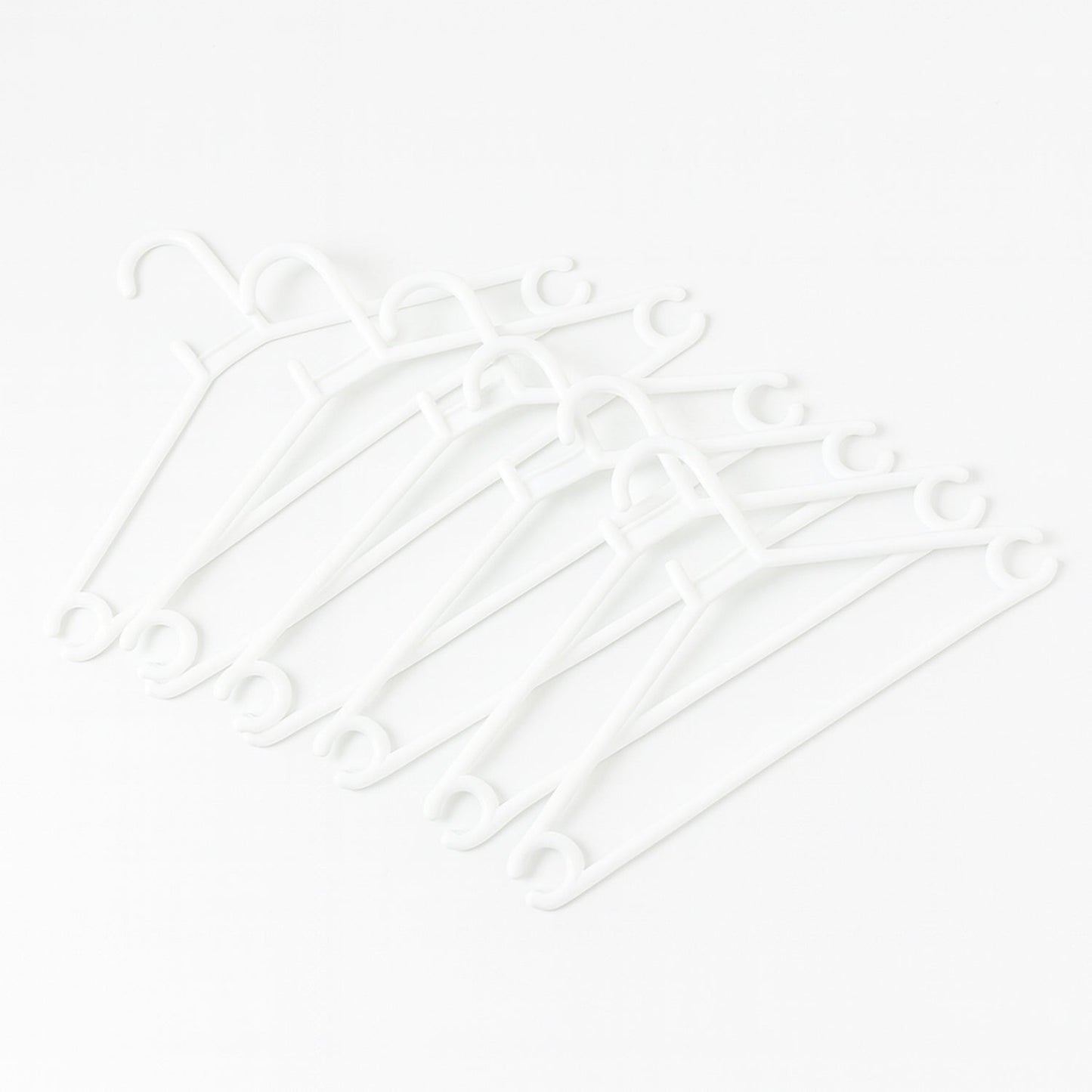 Stack of 6 white plastic clothes hangers ready for use