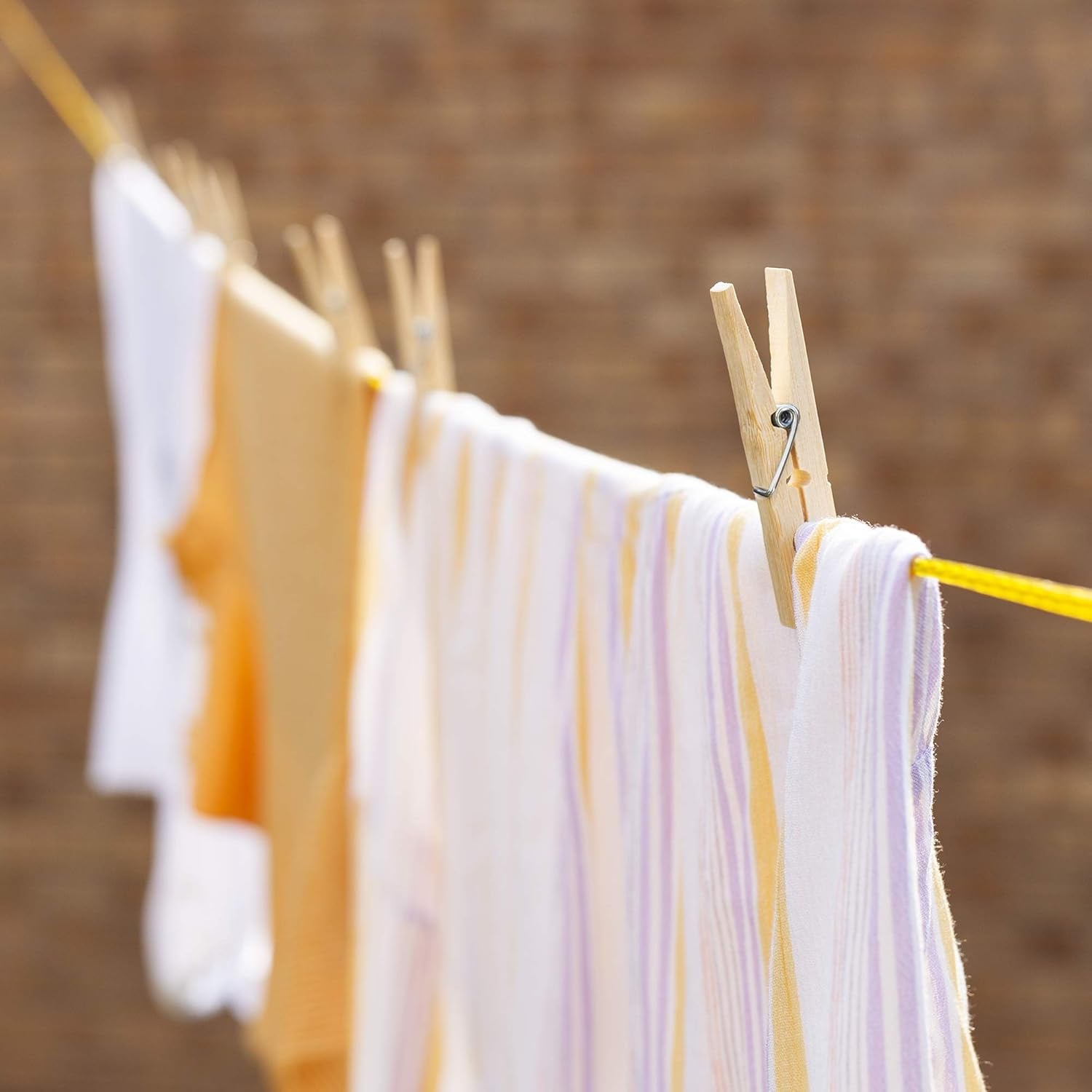 Durable bamboo cloth clips securely holding a heavy fabric blanket on a clothesline.