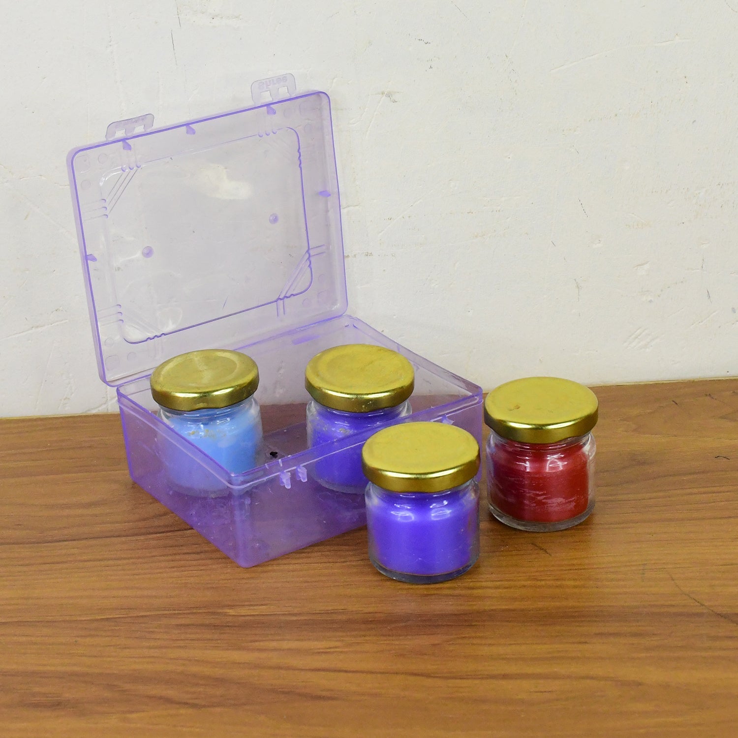 Close-up of wax candle contained in colorful glass jar with gold lid