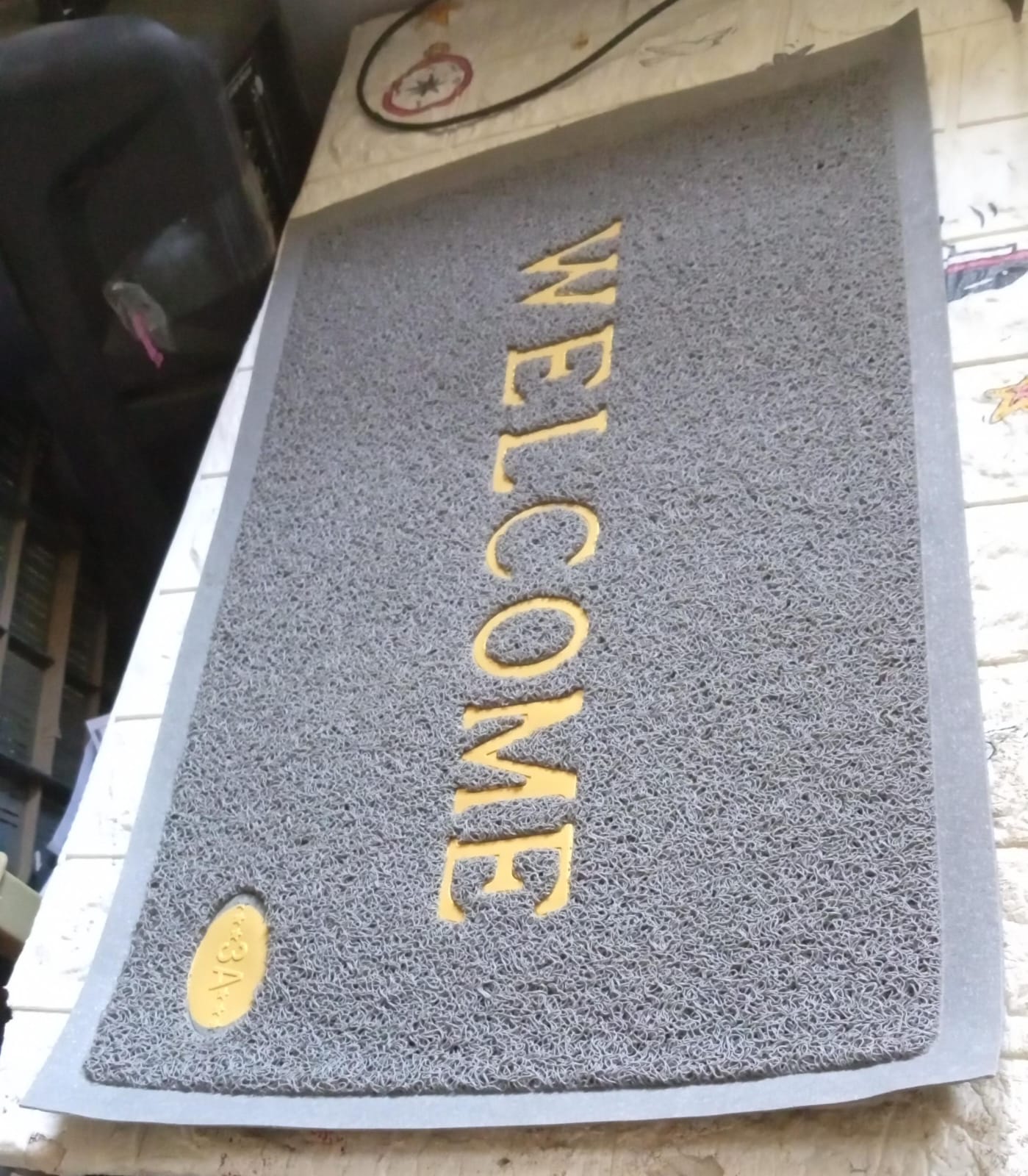 The easy-to-clean Welcome Door Mat with water droplets, demonstrating its quick-dry microfiber material.