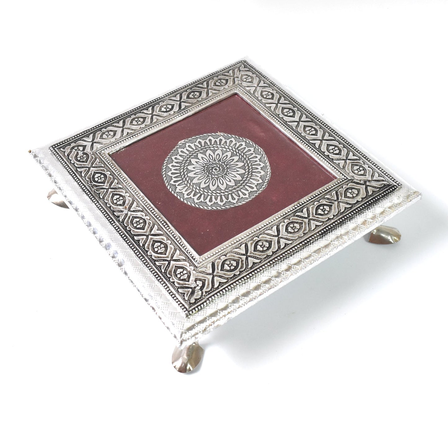 Close-up of the silver pooja chowki, highlighting an embossed peacock motif detail.