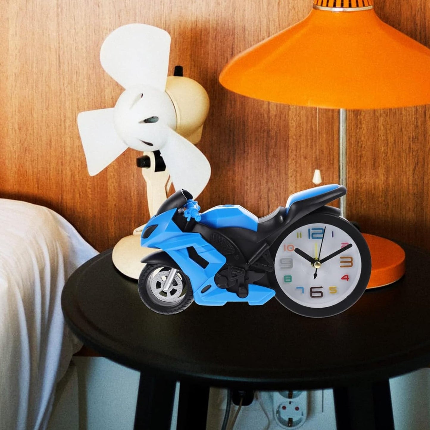 The unique bike engine style clock on a clean white desk next to a pen, showing its suitability for office spaces.