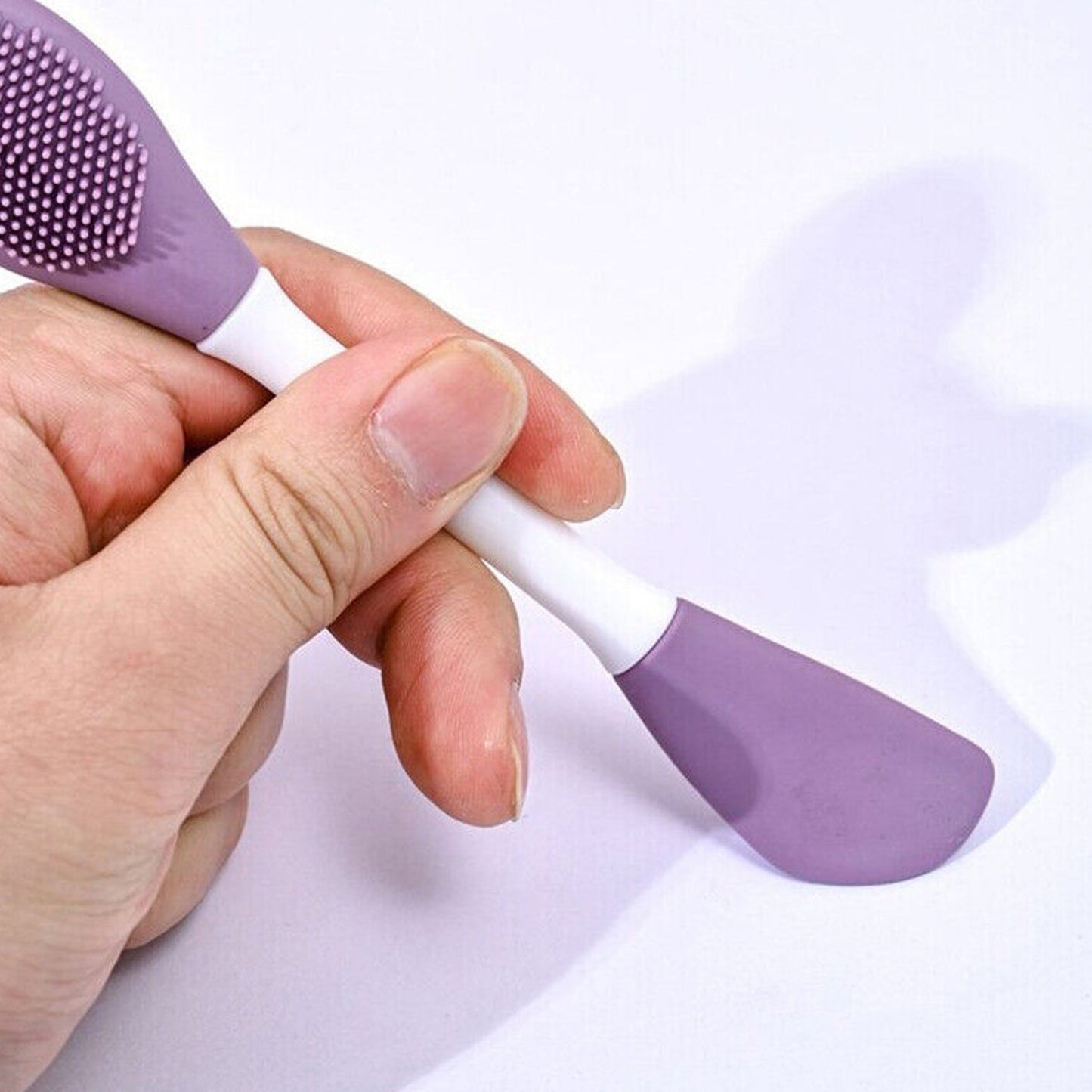 Ergonomic design of the double-headed silicone brush held comfortably for skincare application.
