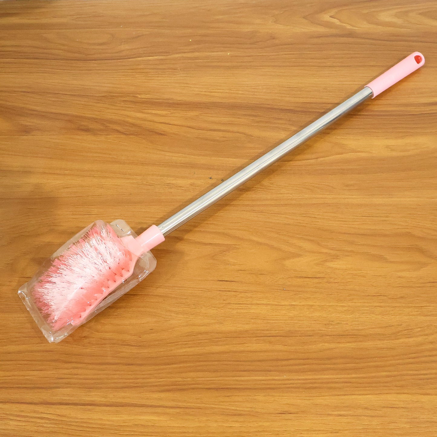 Toilet brush in use cleaning toilet bowl with long handle and splash-resistant head
