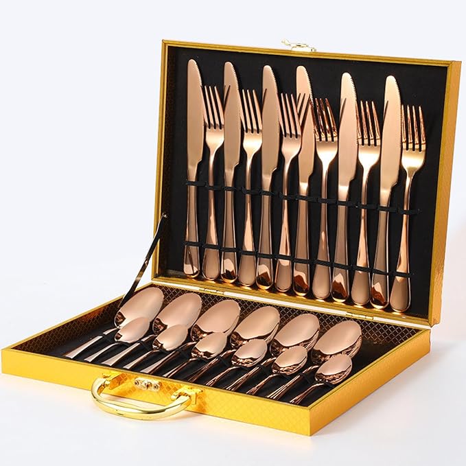 Gold cutlery set laid out on a dining table with a decorative plate.