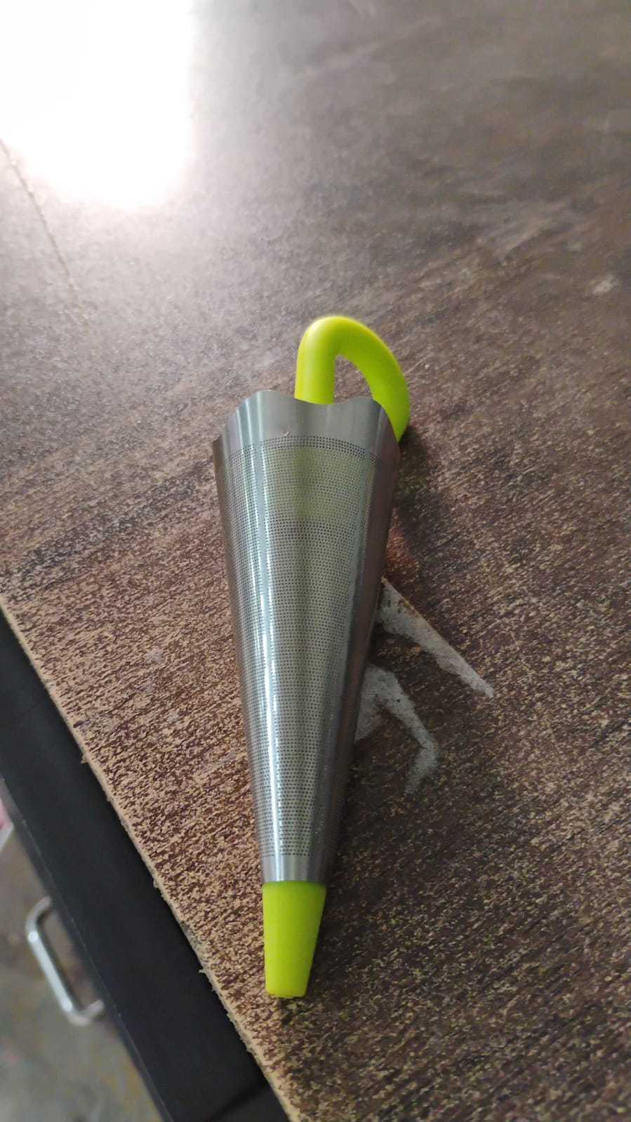A single umbrella tea strainer isolated on a clean white background.