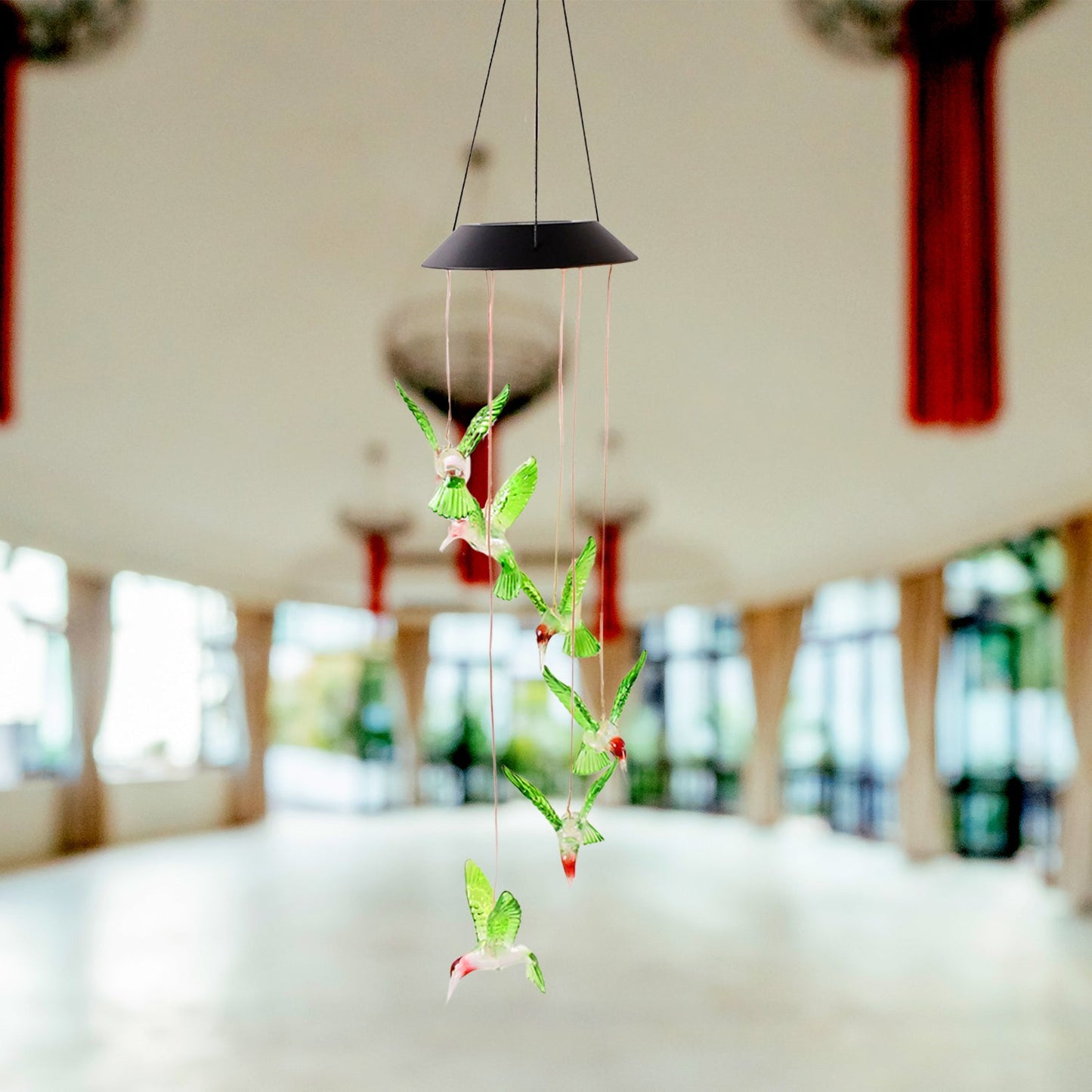 Decorative solar powered hummingbird wind chime hanging in garden